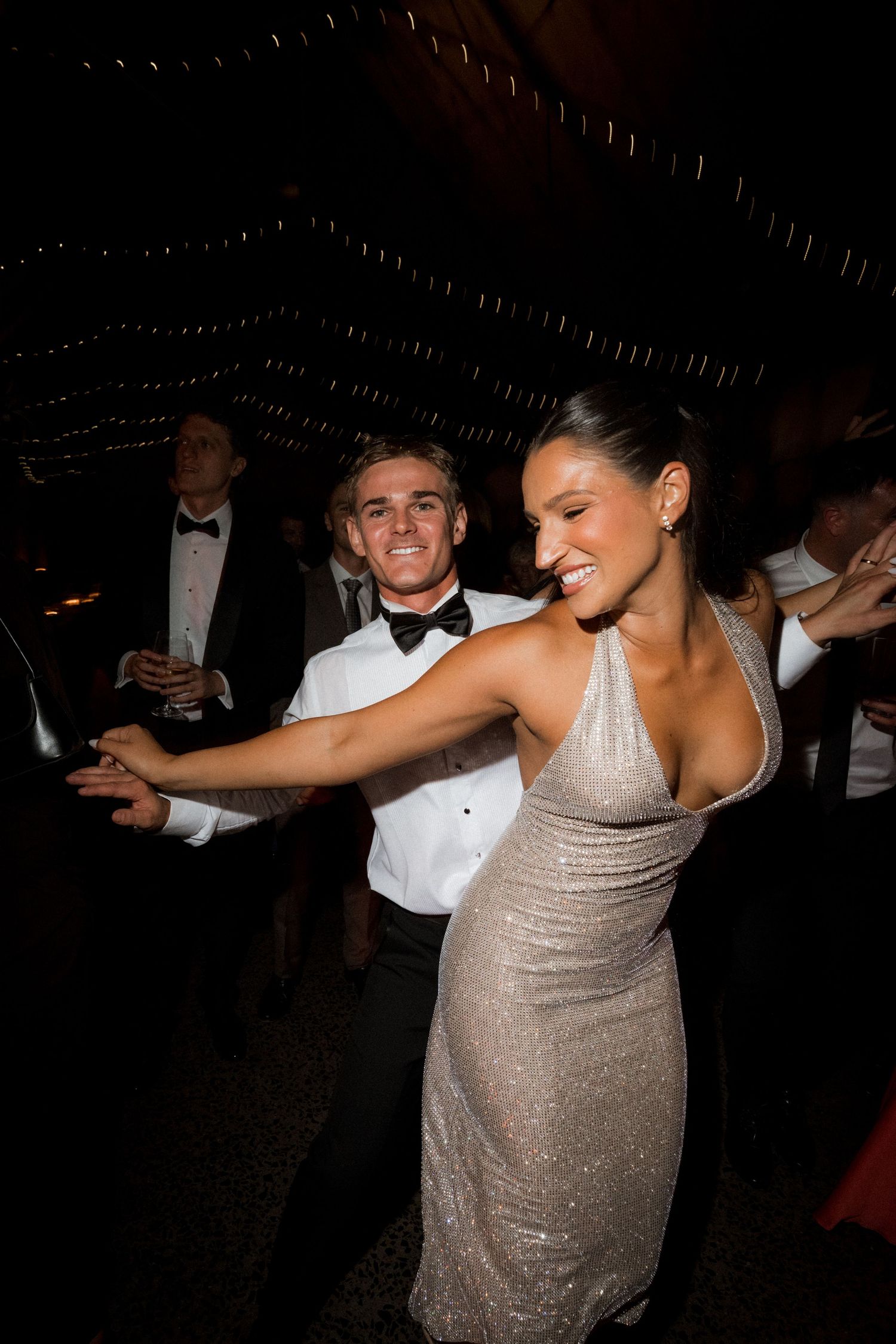 Person in a sparkly silver dress dancing and twirling on a dark dance floor.