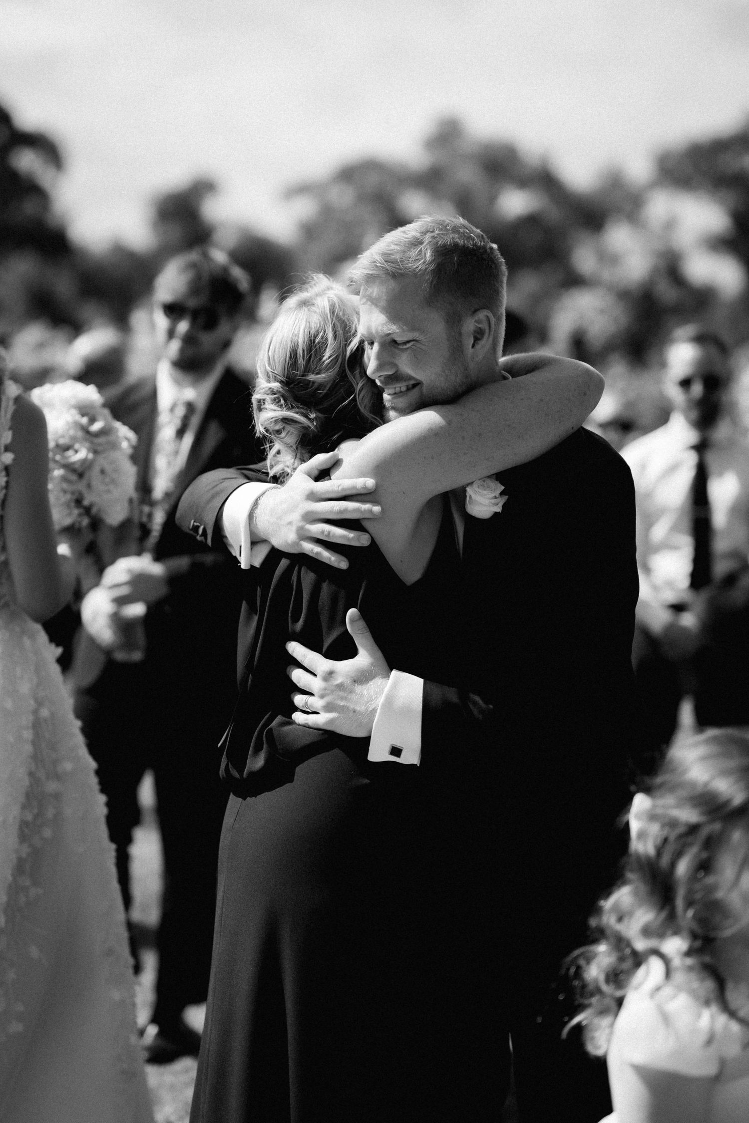 A tender embrace shared during a wedding ceremony as guests look on.