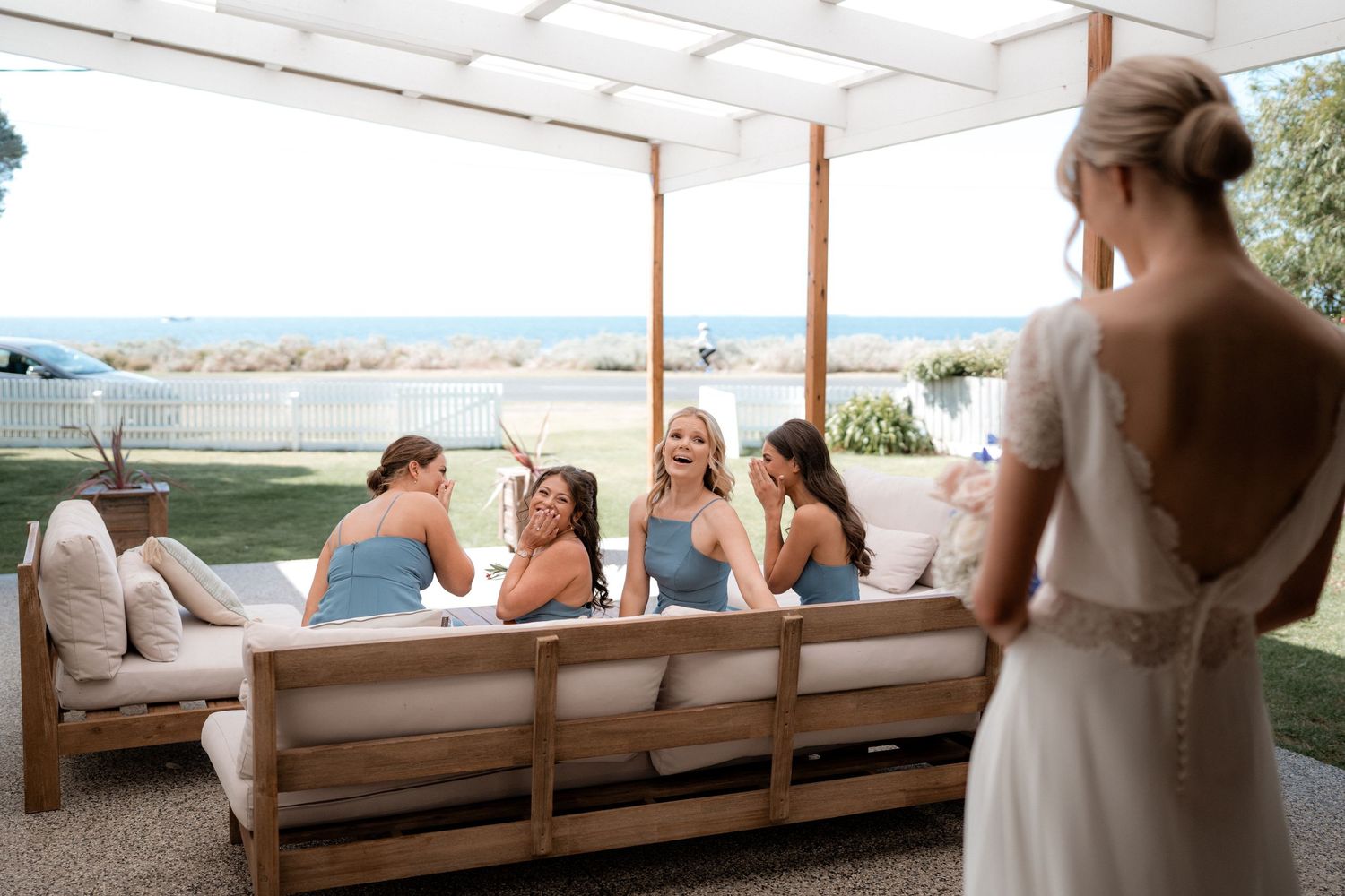 A group enjoying a relaxed moment on an outdoor patio couch overlooking the ocean.