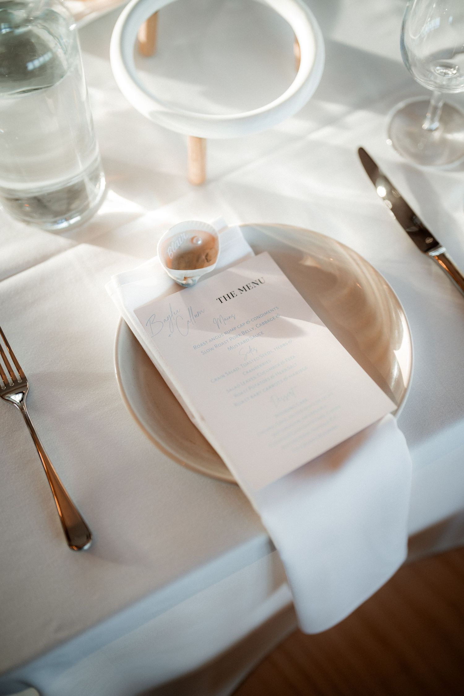 Wedding reception place setting with white napkin and menu card on elegant dinnerware.