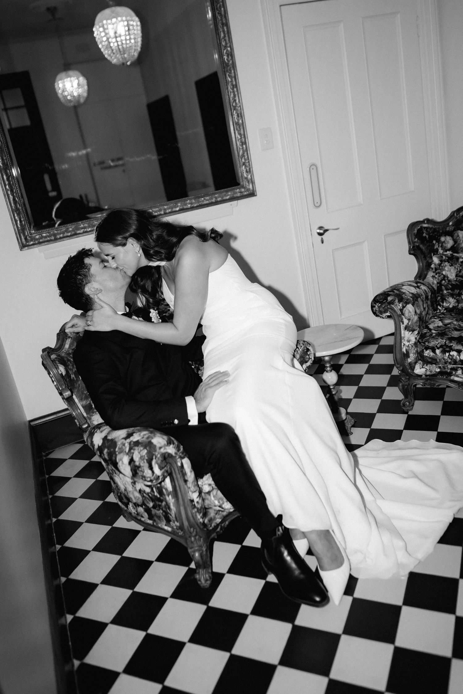 Black and white dance sequence on checkered floor showing playful wedding celebration.