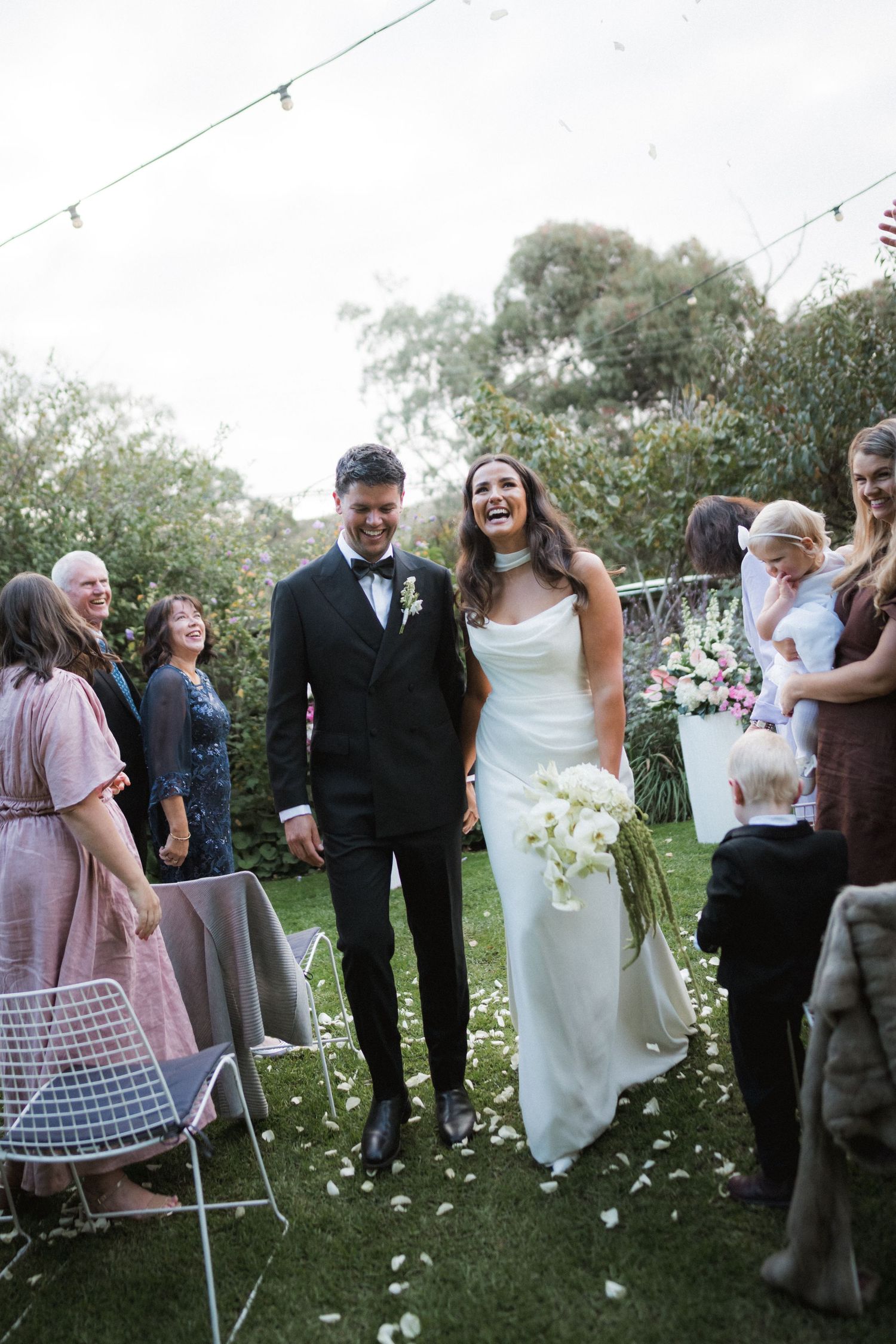 A sequence of outdoor wedding celebration photos showing guests mingling on a lawn with decorative string lights.