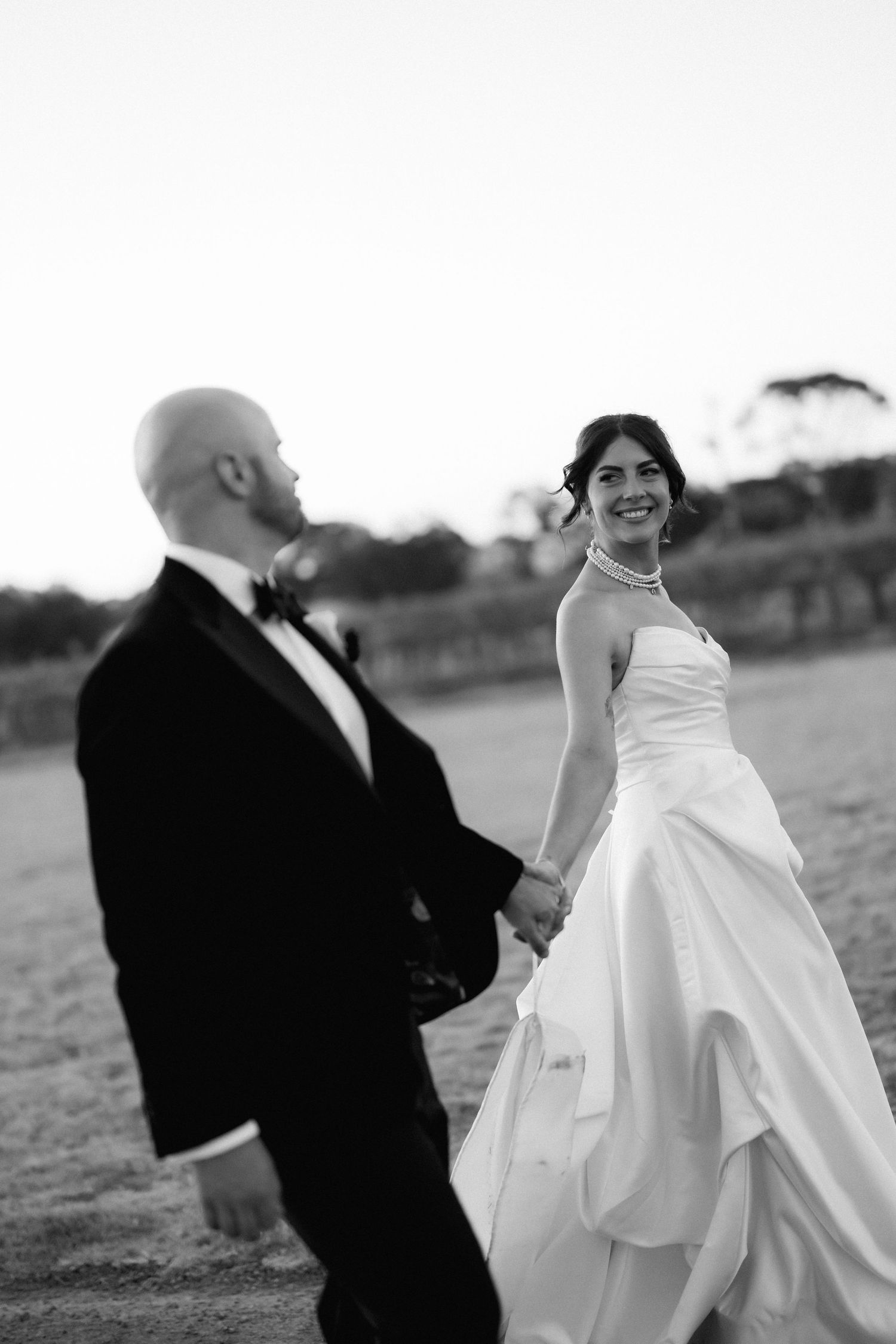 Black and white wedding photo series showing romantic moments between newlyweds in an outdoor field setting.