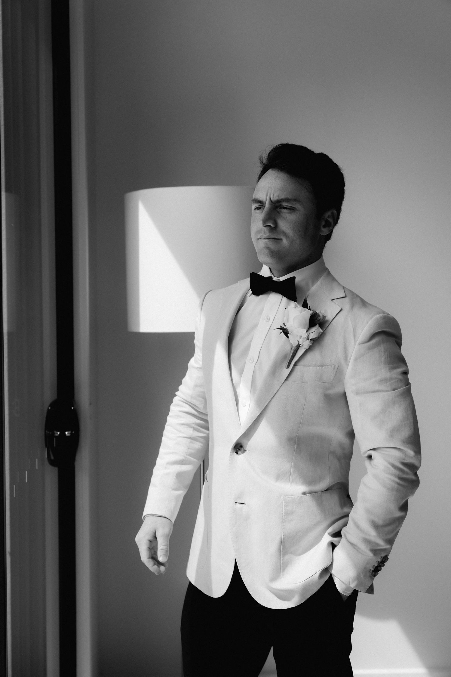 A series of dramatic black and white portraits showing a person in a white suit jacket against a light background.