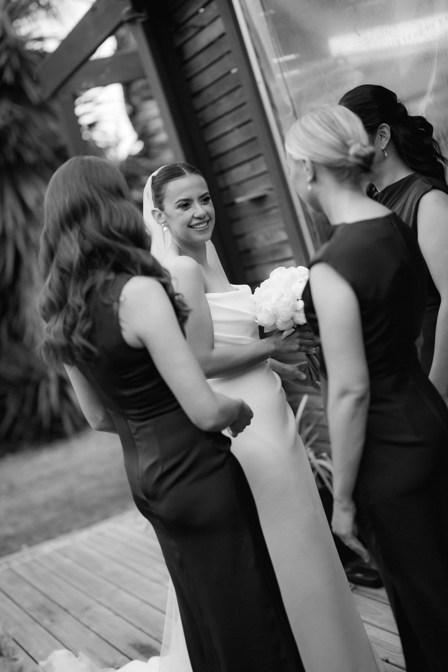 Black and white candid shots of a wedding party dancing and laughing together at a reception.