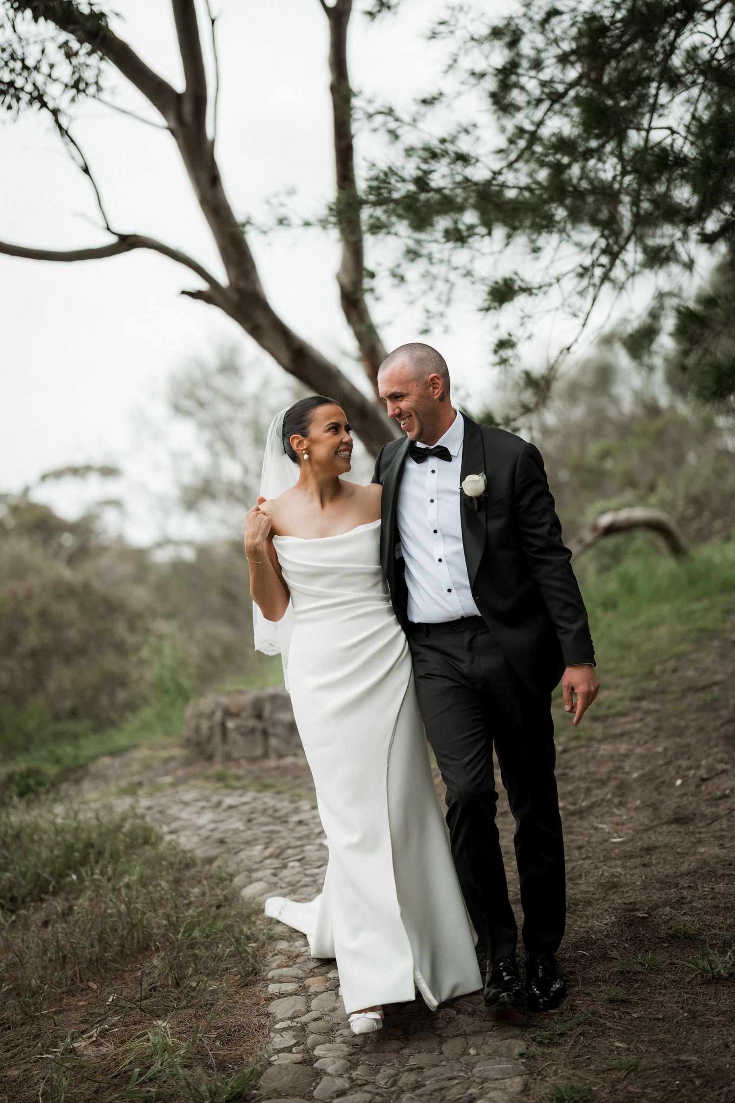 Romantic wedding portrait on a rustic path surrounded by eucalyptus trees.