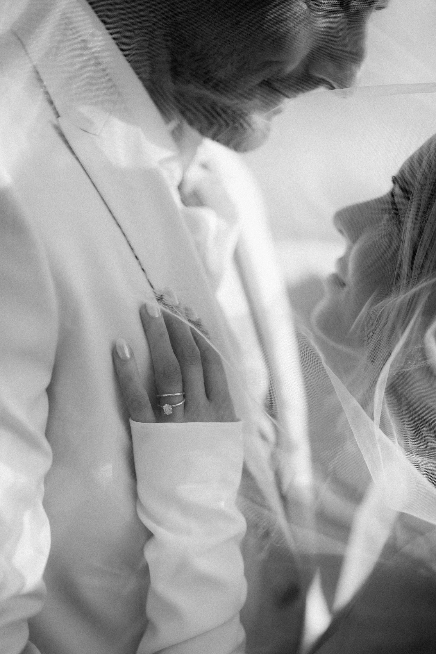 Intimate black and white close-up of newlyweds showing wedding ring detail.