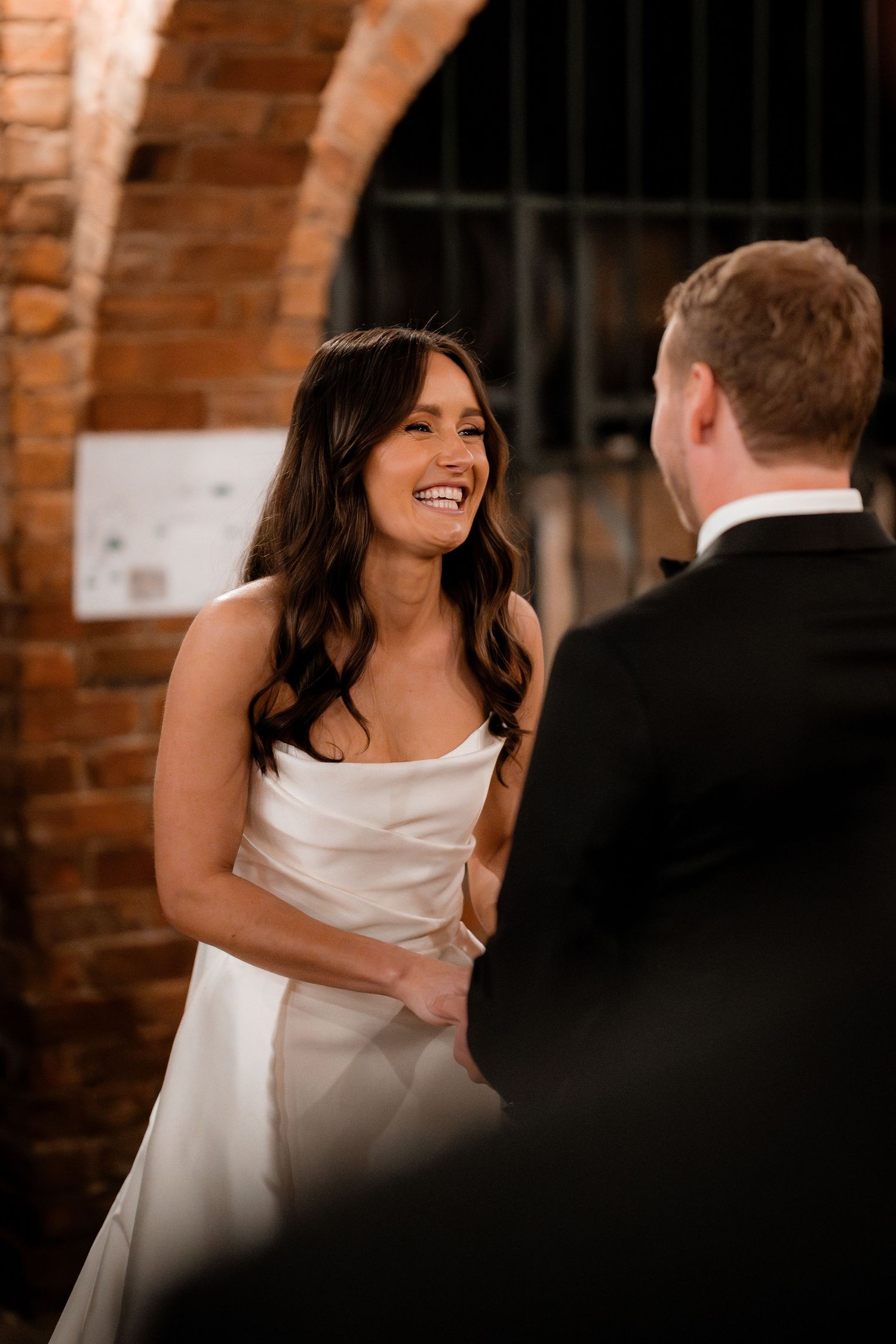 A joyful moment shared between a couple in a rustic brick venue during their wedding.