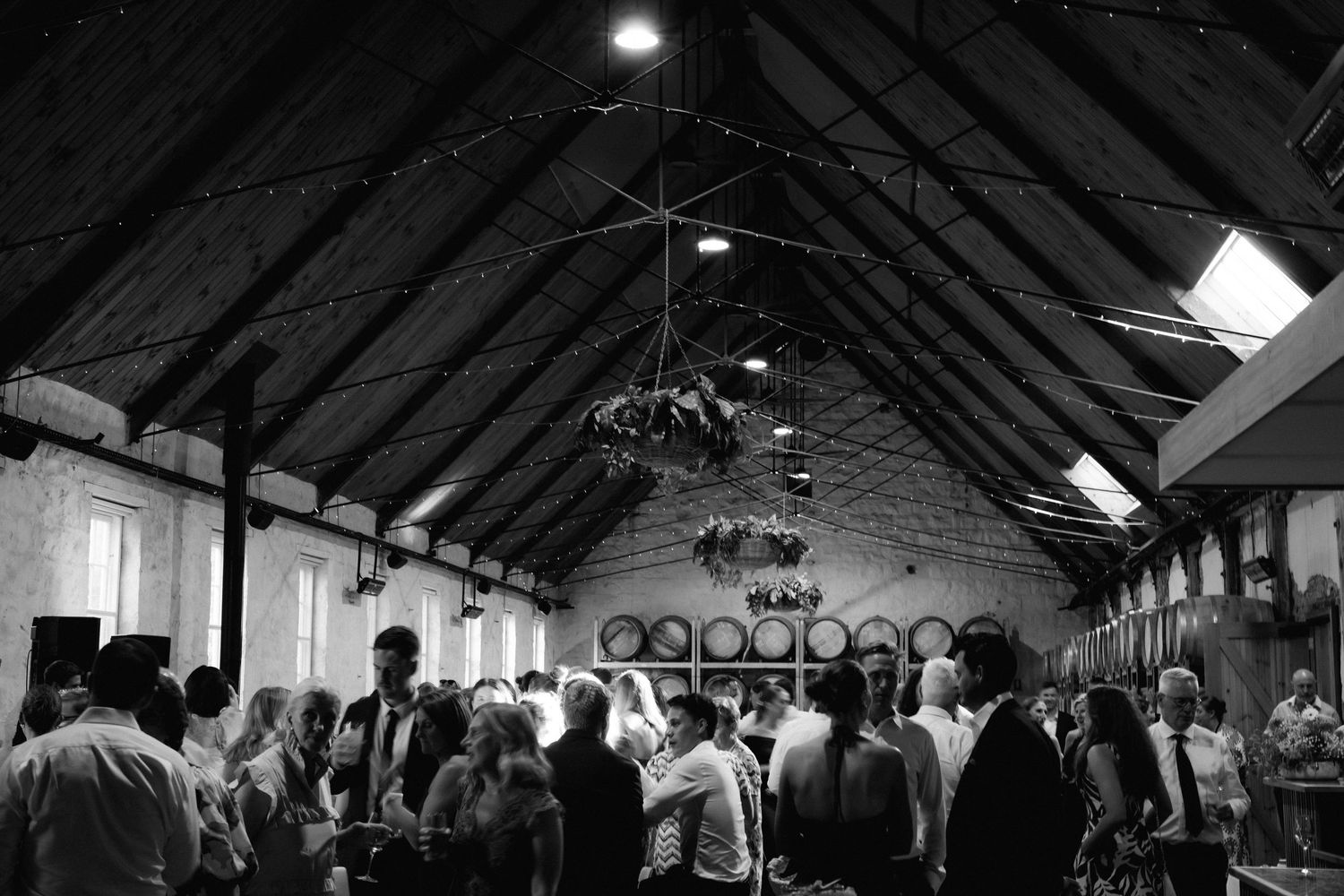 Wedding reception venue with exposed wooden beams and ceiling lighting creating a rustic atmosphere.