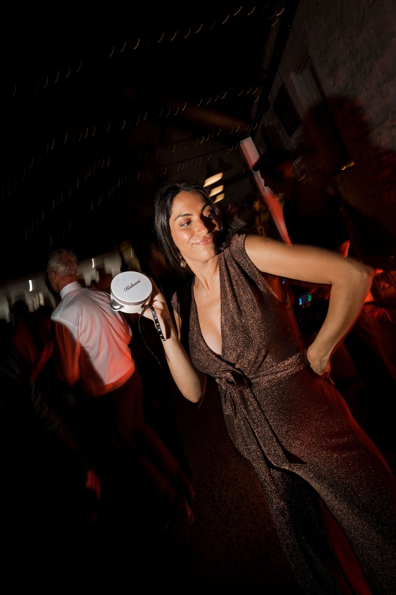 People dancing and celebrating at a dimly lit wedding reception party in a rustic venue.
