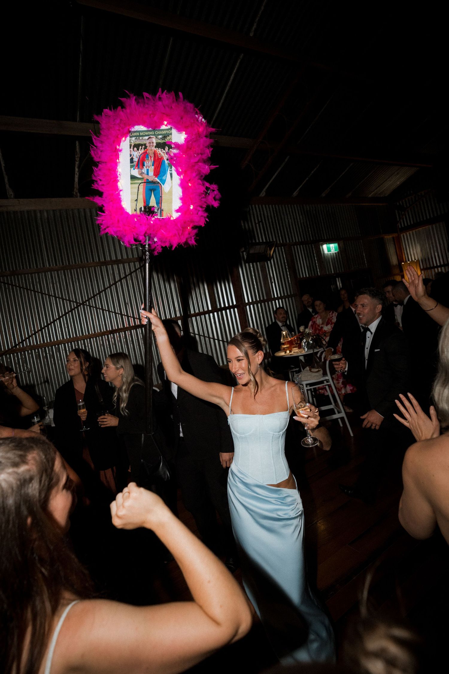 A sequence of photos showing a person in a light blue dress dancing with a bright pink bouquet at a dimly lit reception.