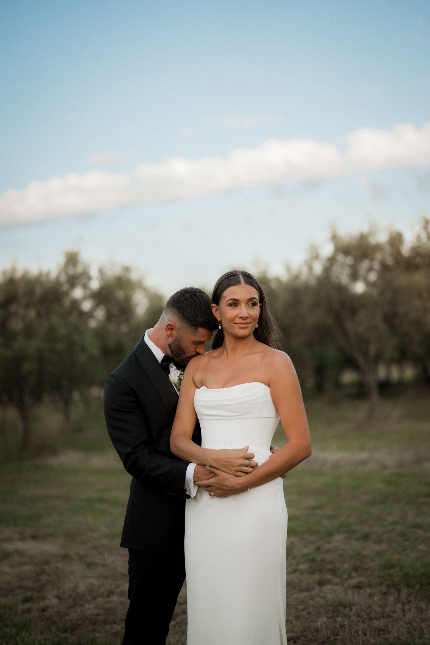 Intimate wedding portraits captured in warm lighting at an outdoor orchard setting.