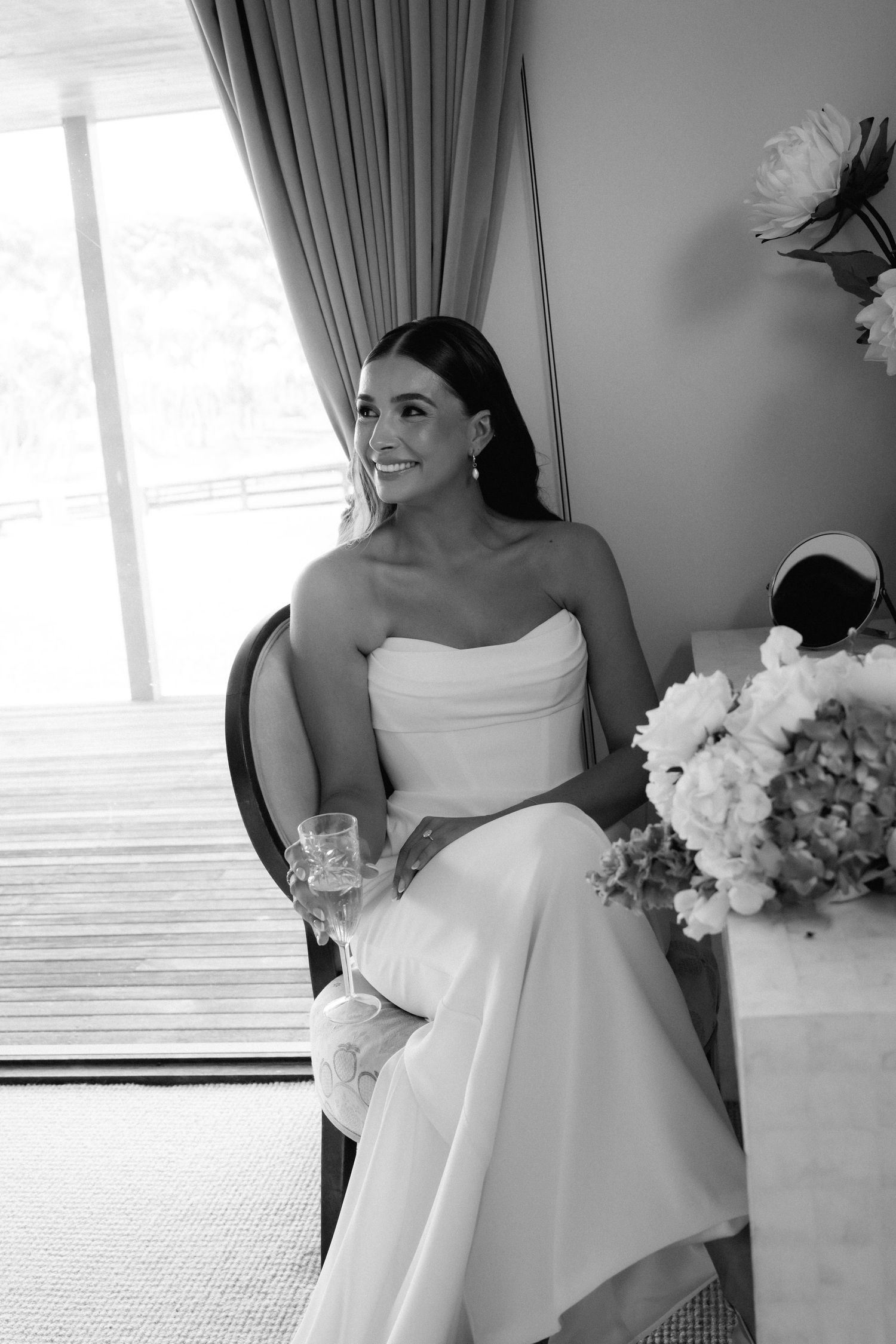 Elegant white wedding dress details with ruffles and strapless neckline in natural window light.