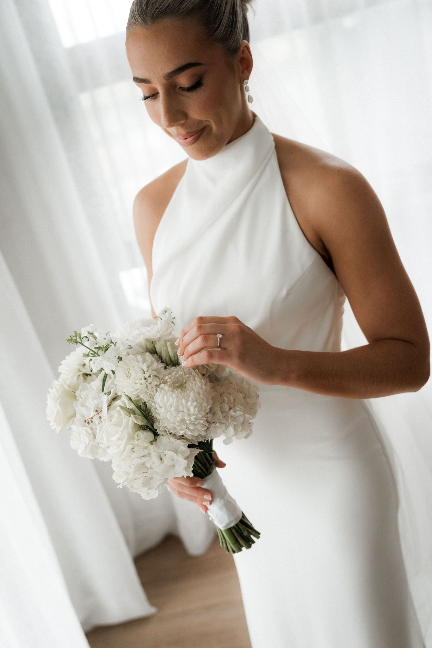 Close-up shots of a bride in a sleek white wedding dress holding a white floral bouquet.