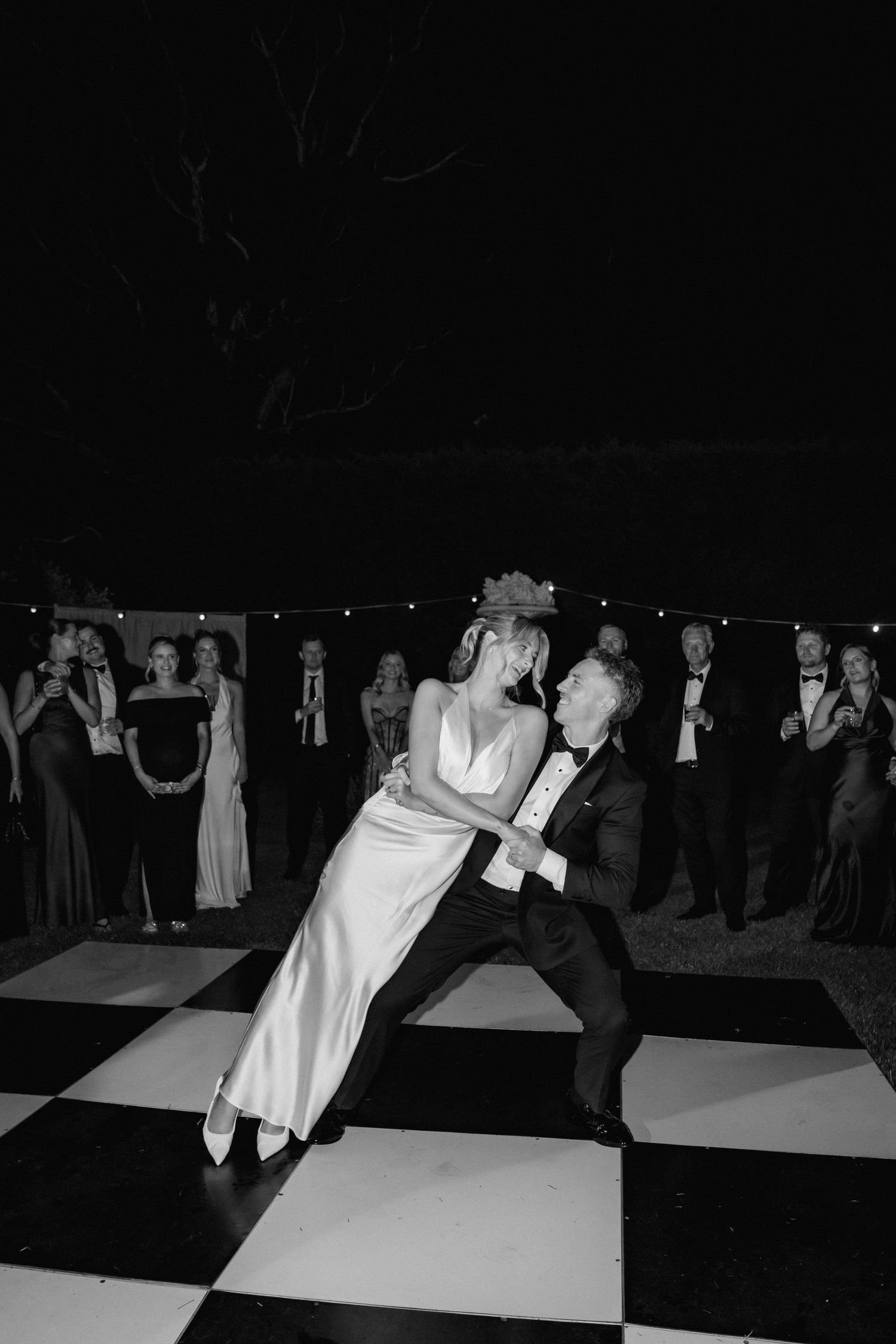 Wedding guests dancing on a black and white checkered dance floor at night.