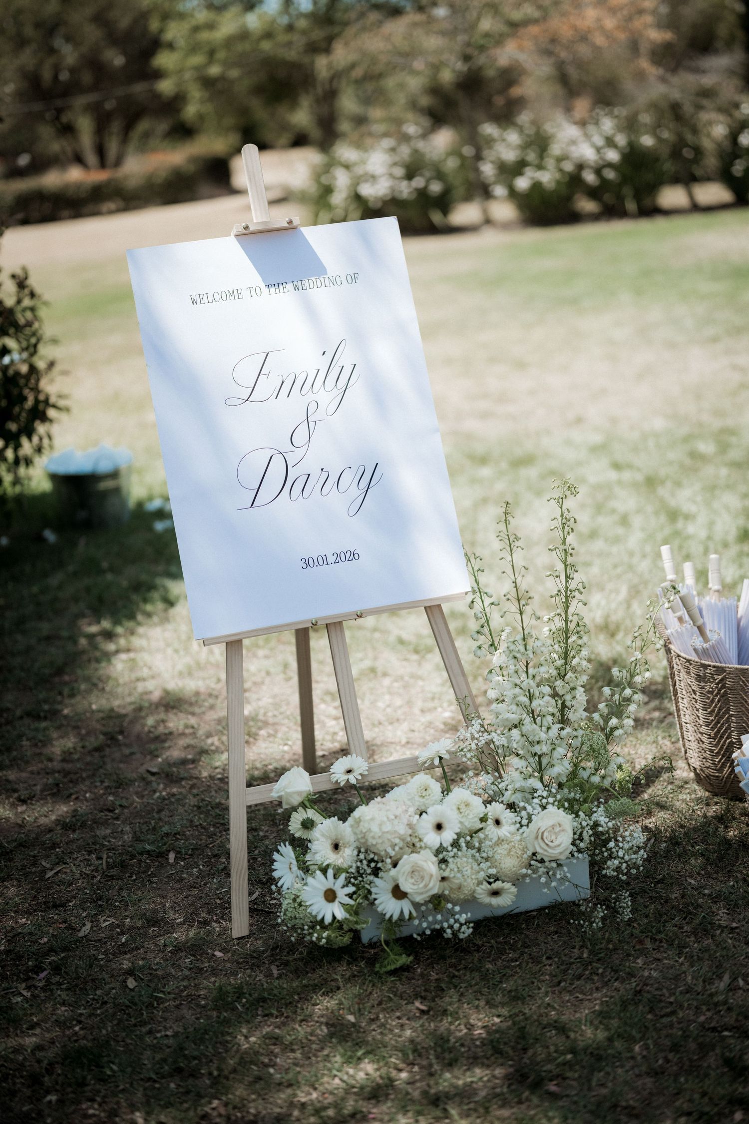 Elegant wedding signage with floral decorations displayed on easels in an outdoor garden setting.