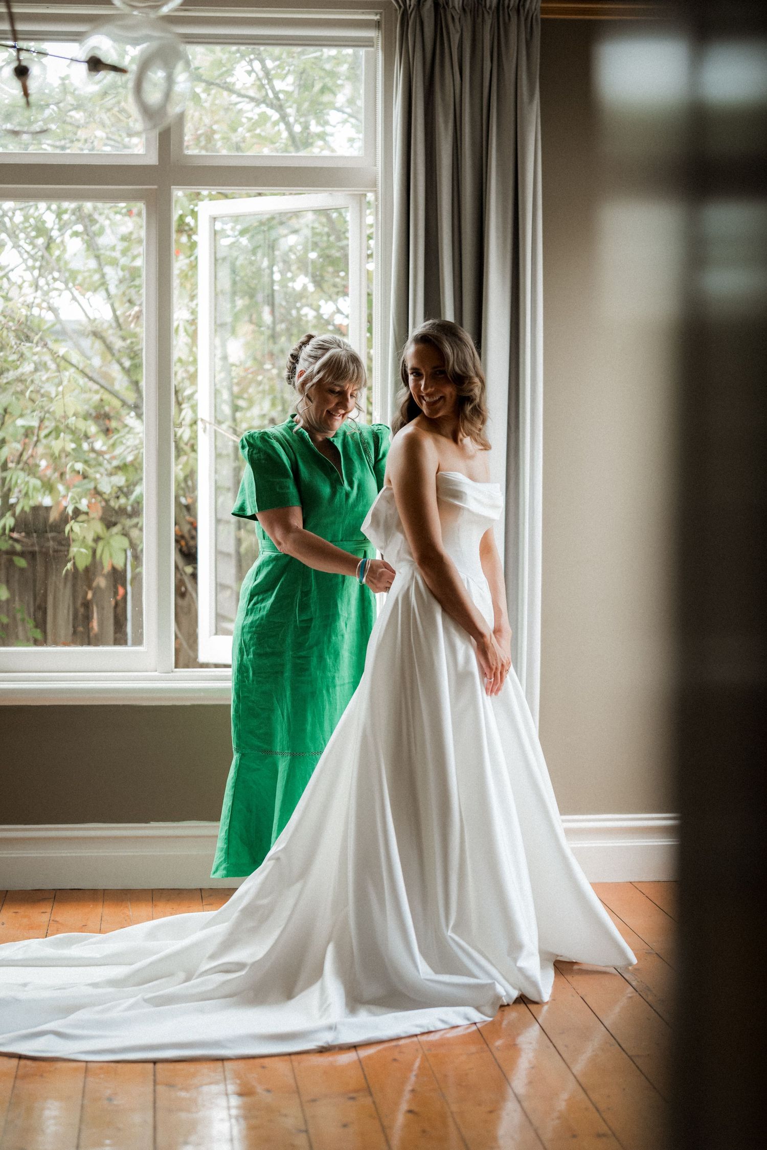 A sequence of photos showing two people in white and green dresses sharing candid moments by a window.