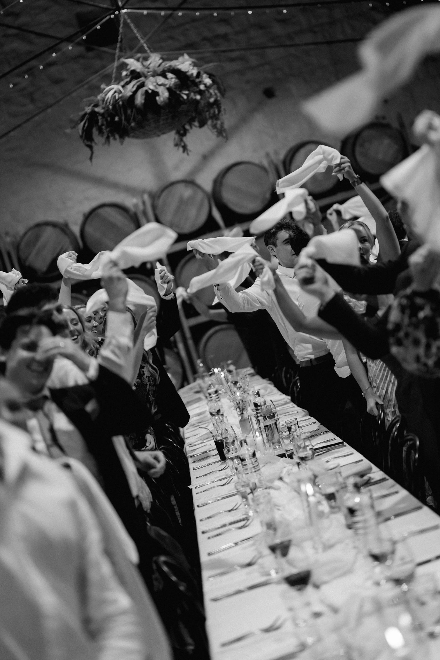 Black and white reception table setting with wine glasses and string lights overhead.