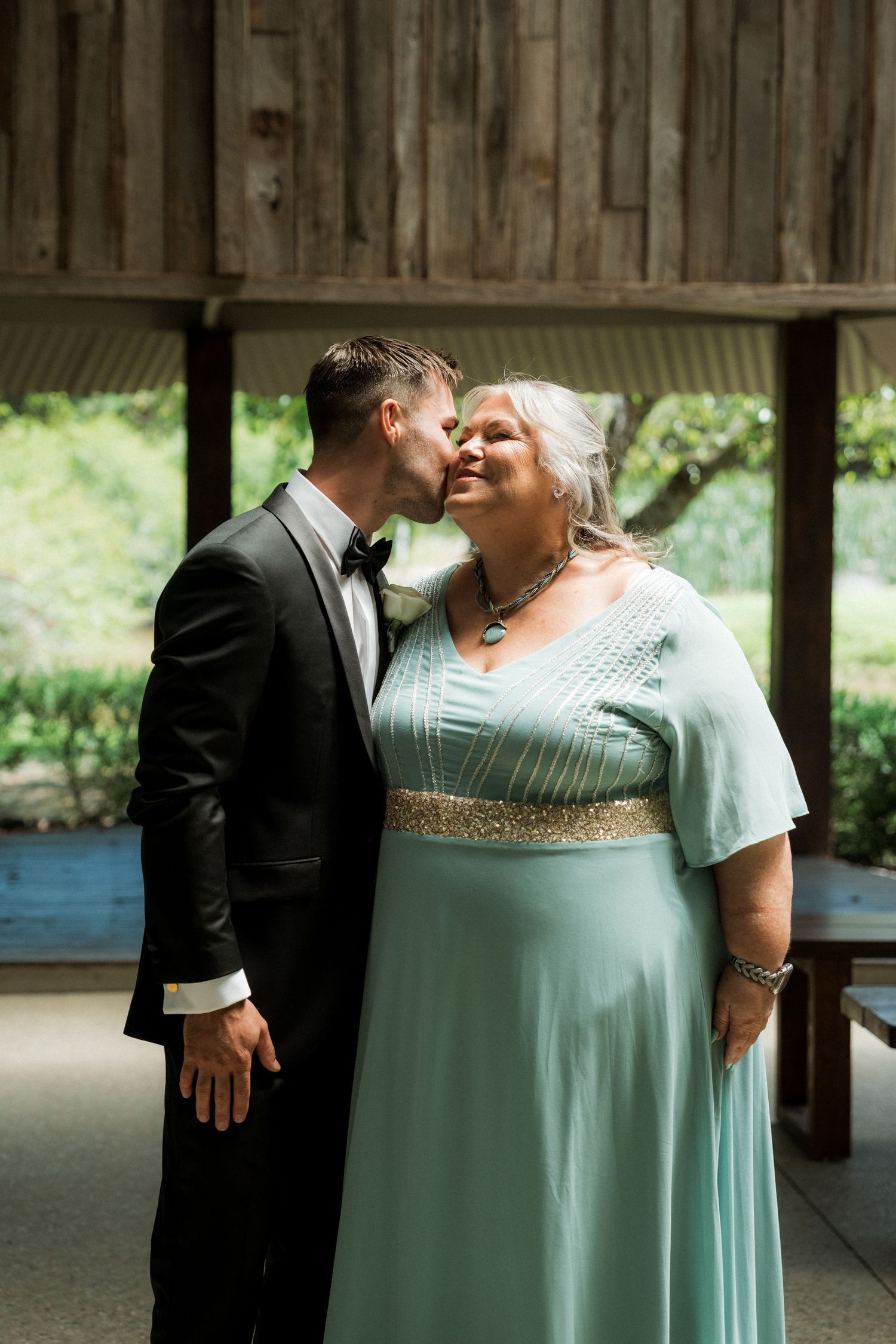 A romantic couple shares an intimate moment in a covered outdoor setting, with the person wearing a mint green dress.