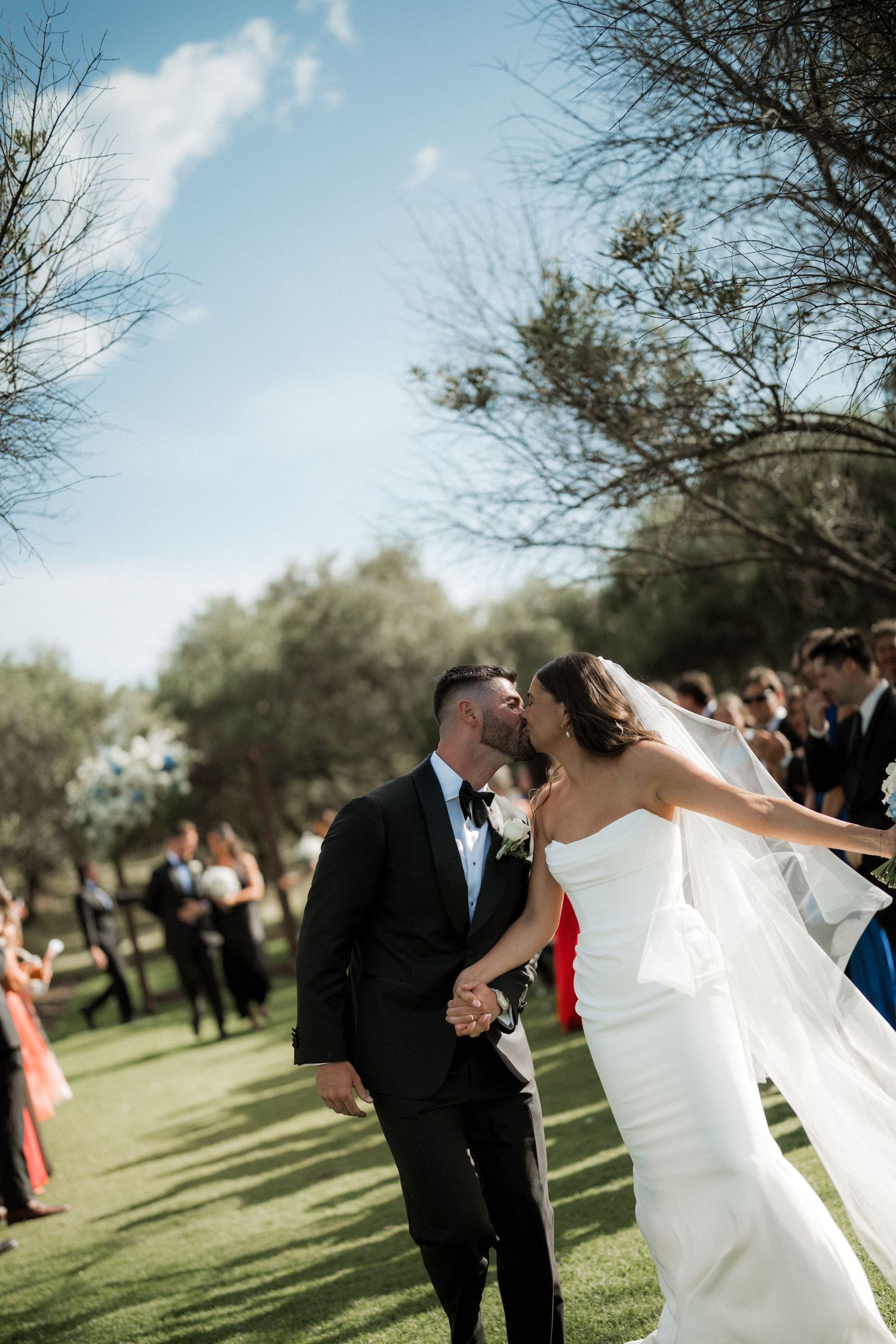 Wedding couple shares romantic moments in a sunny outdoor garden setting.
