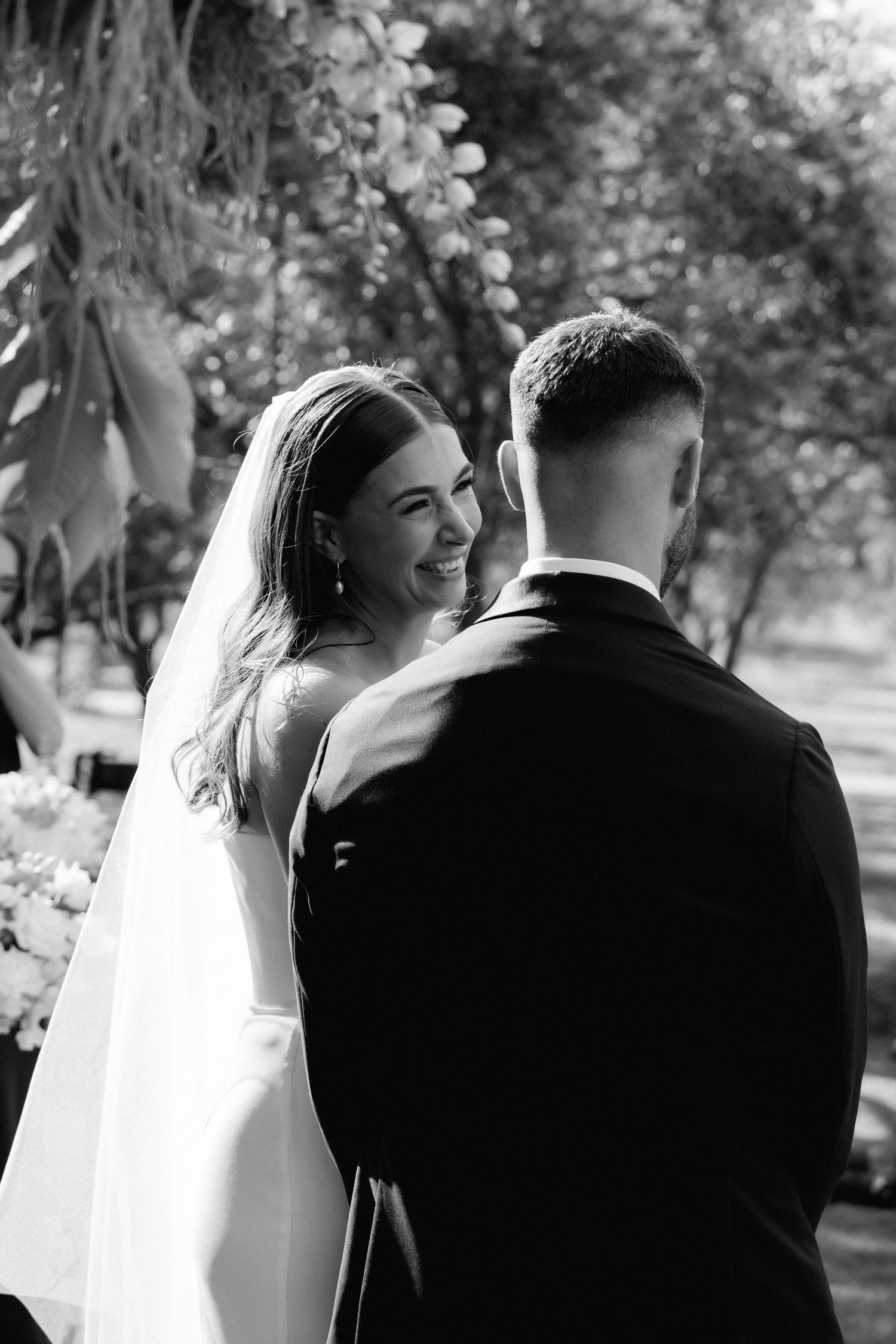 Black and white wedding photos capture tender moments between newlyweds in an outdoor setting.