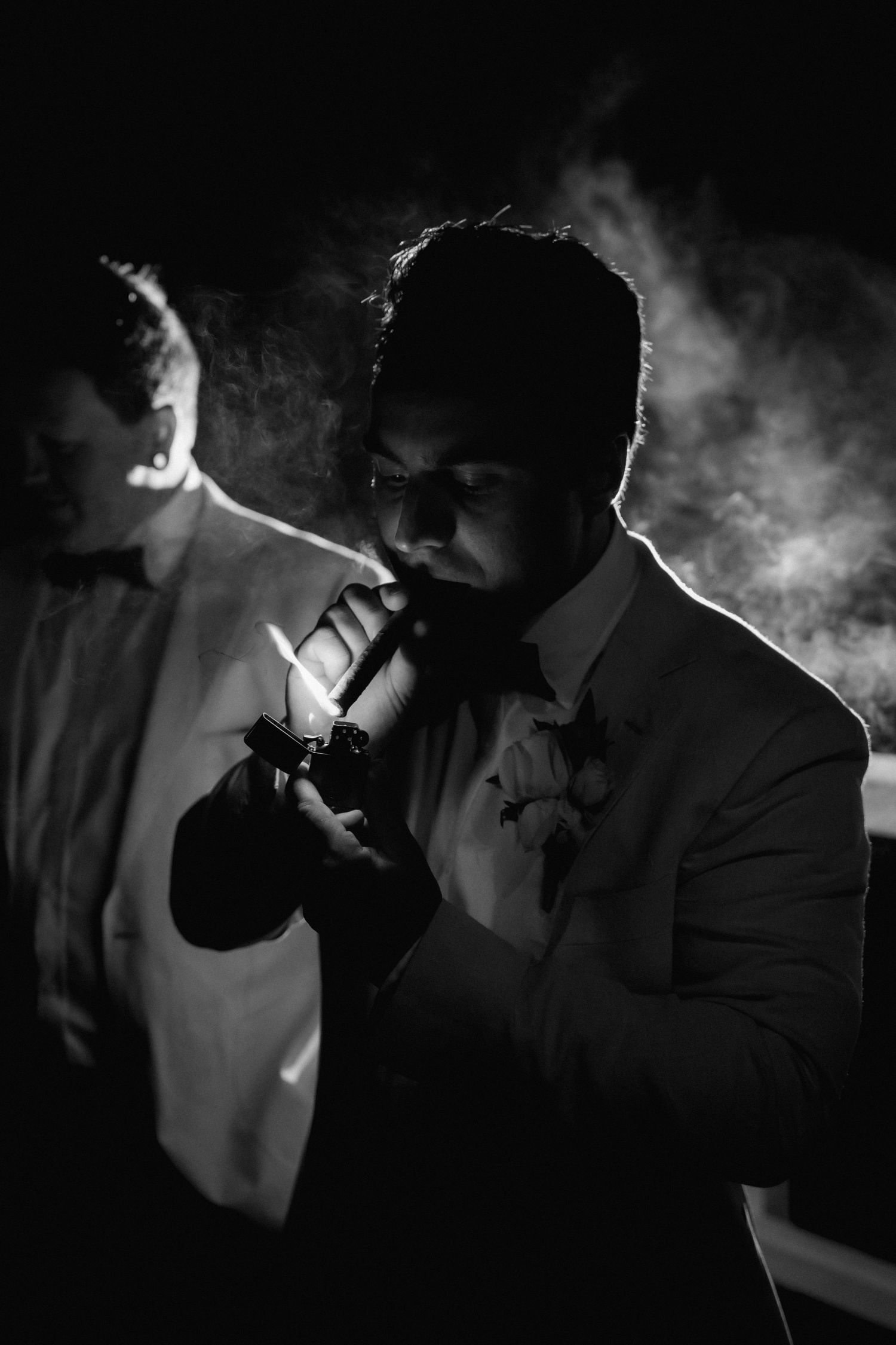 Dramatic black and white silhouettes of a person smoking in formal attire.