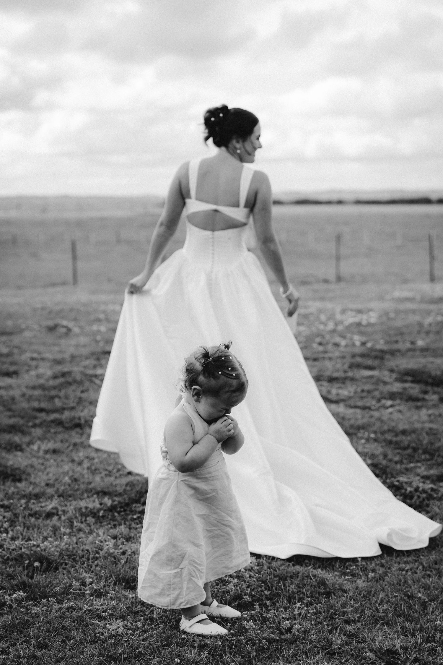 White wedding dress flowing in the wind across a grassy field in black and white.