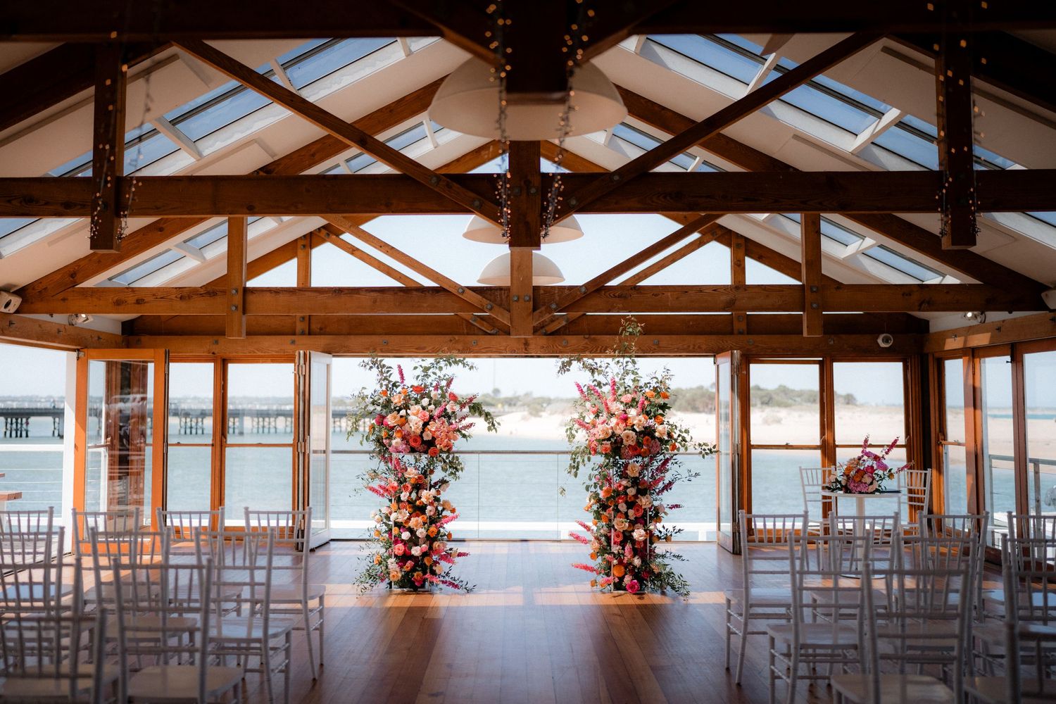 Panoramic view of an empty wedding venue with wooden beams and skylights.