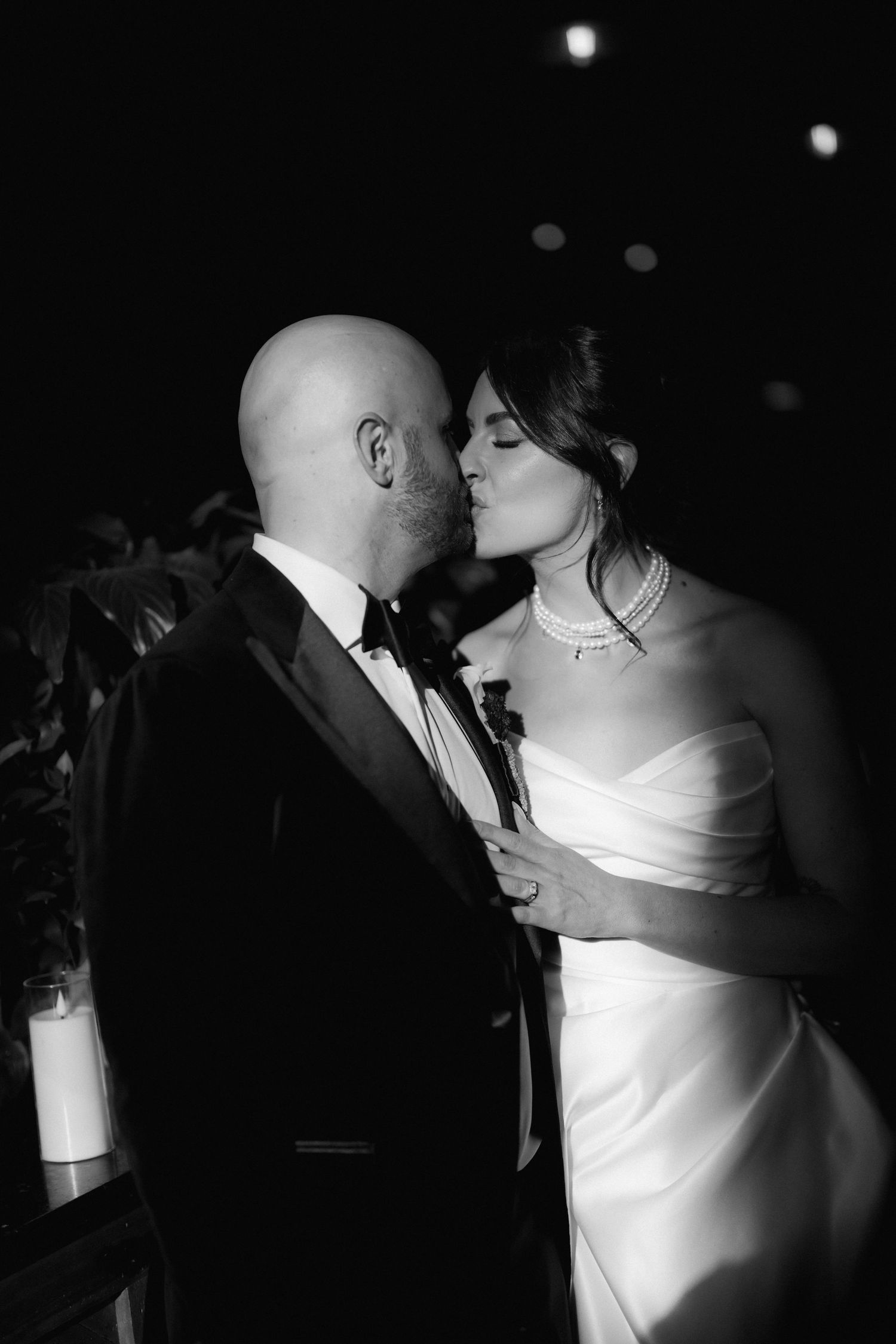 A romantic black and white sequence shows a couple sharing an intimate kiss in formal wedding attire.