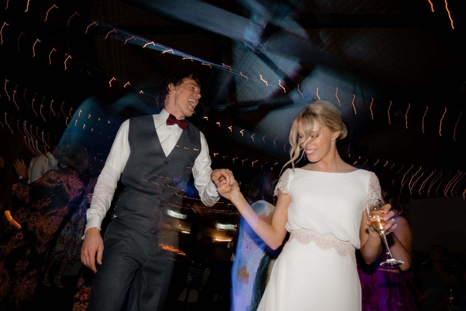 A couple dances together at their wedding reception under moody lighting.