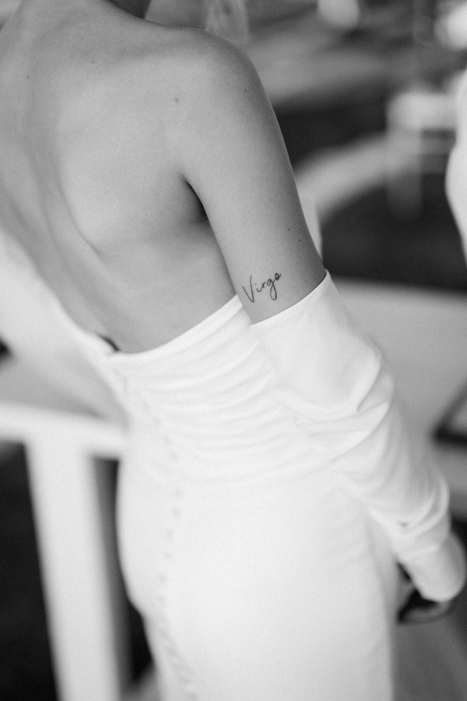 Close-up black and white photo of small script tattoo on side of bride's ribcage.
