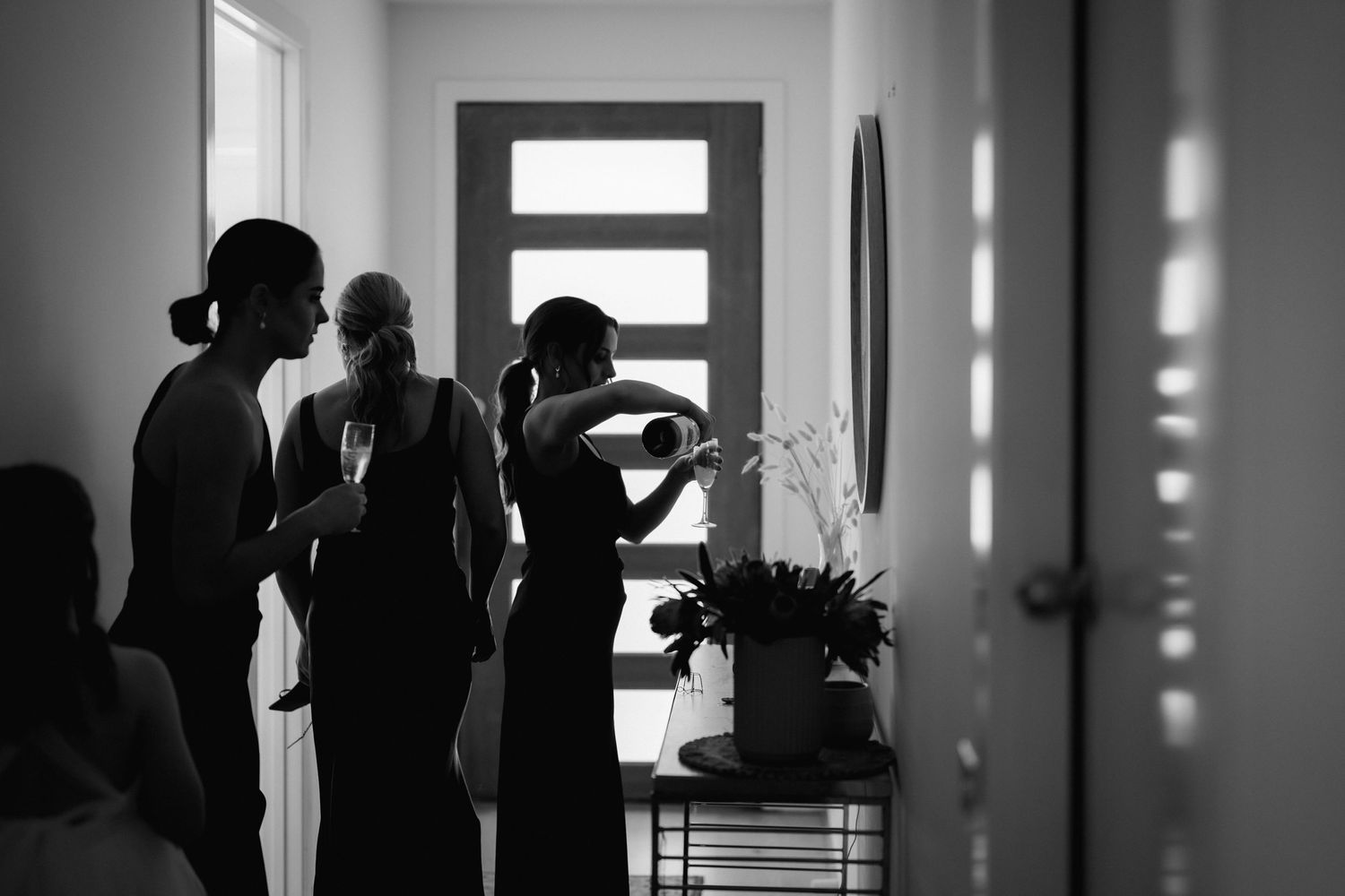 Silhouettes of people gathered in a modern interior hallway with vertical light panels.
