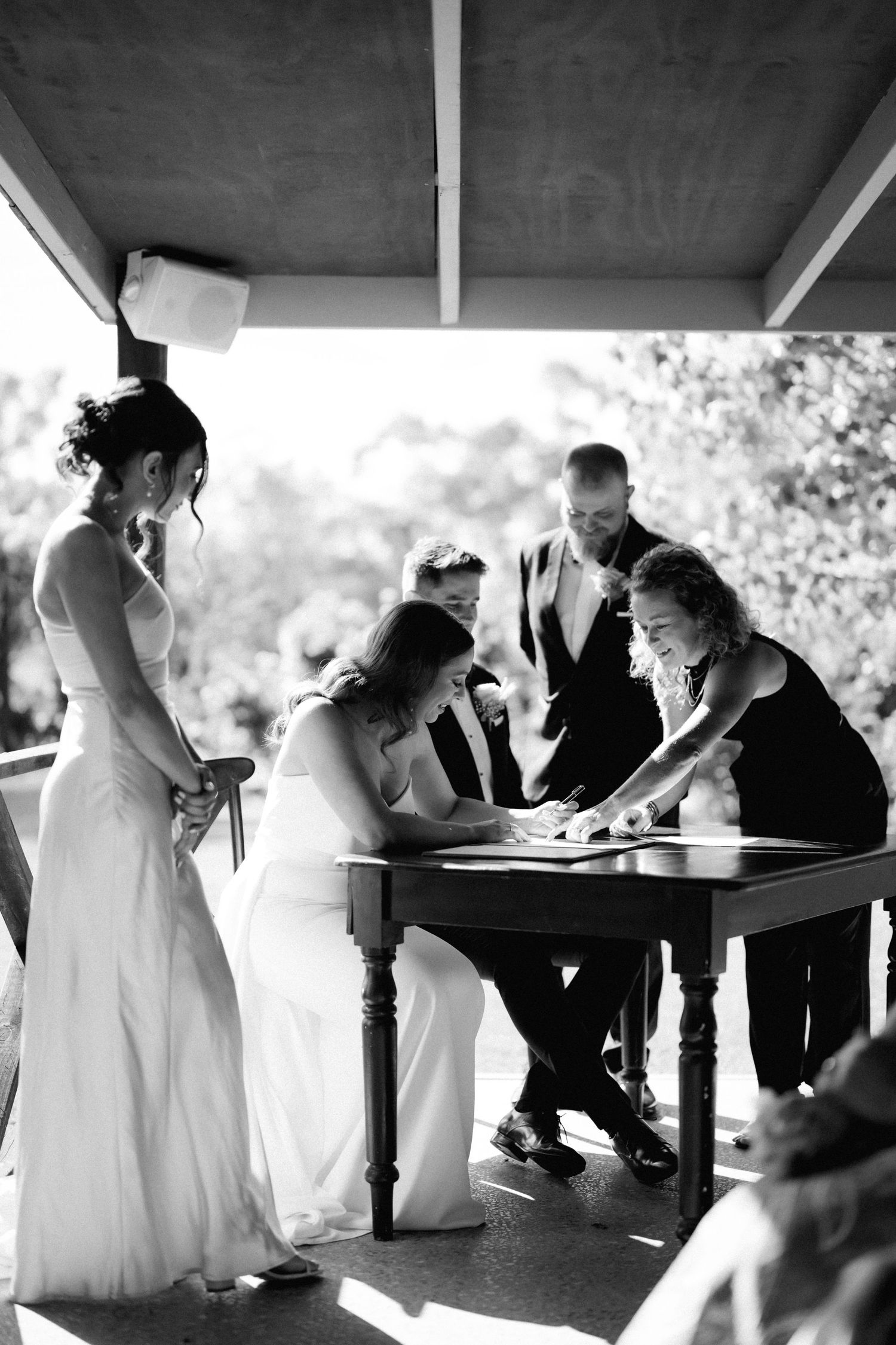 A couple signs documents during their wedding ceremony under a covered porch.