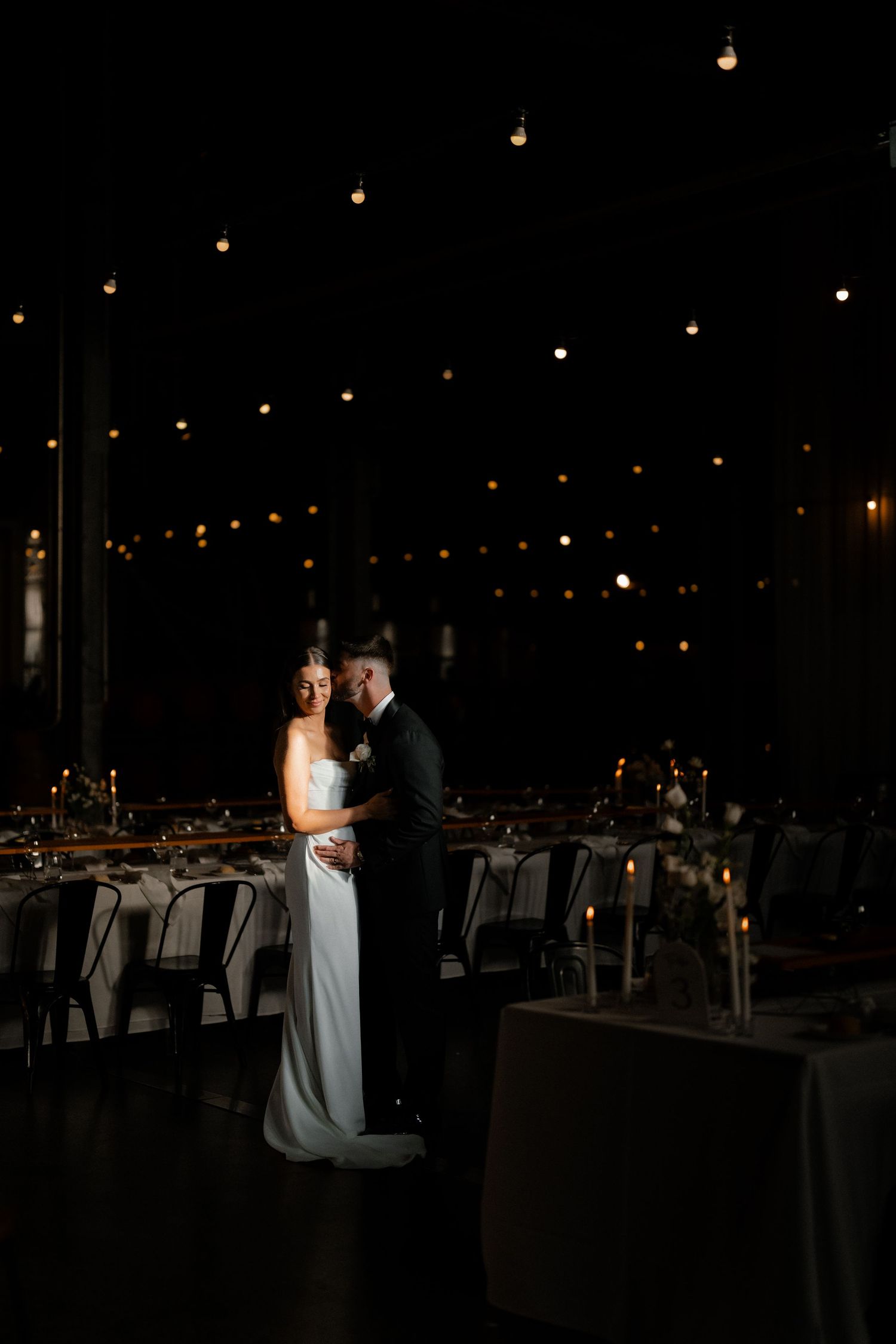 A romantic first dance under twinkling lights at an evening wedding reception.