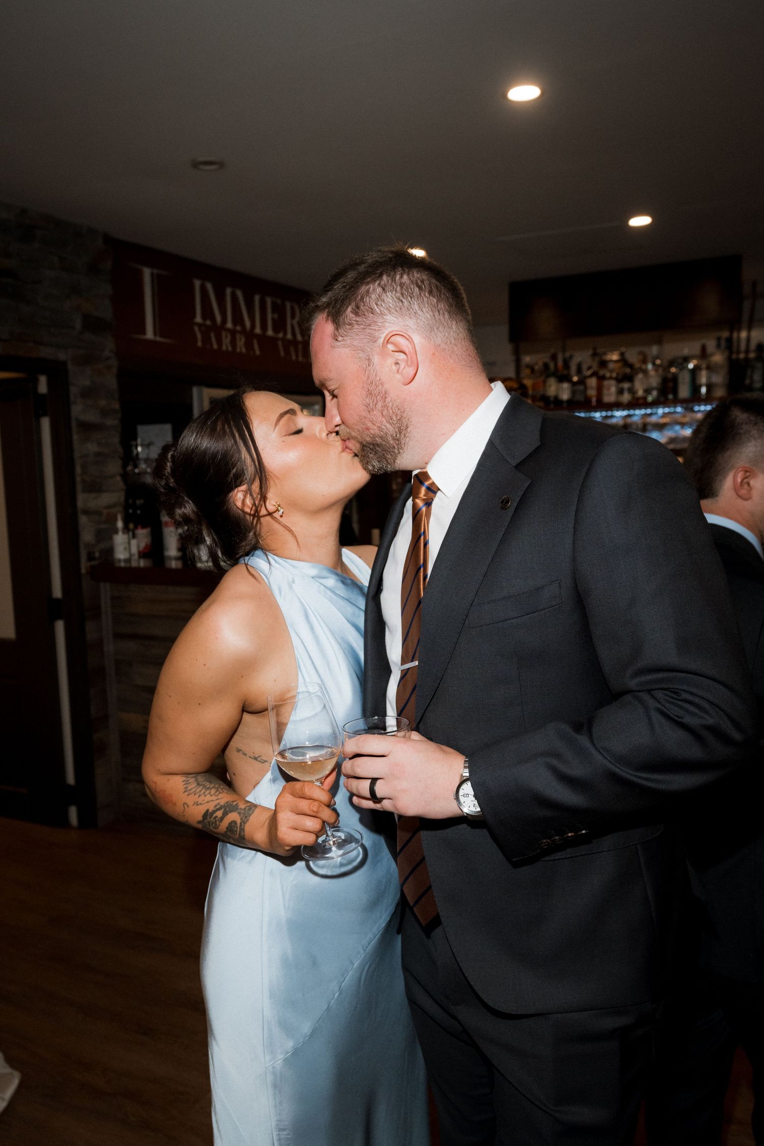 A couple shares a romantic dance moment in formal attire at an indoor venue.