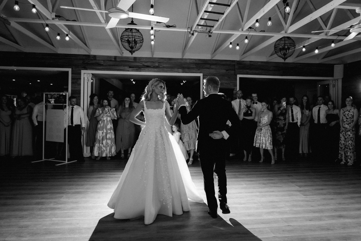 Black and white photo of a first dance in an elegant reception hall.