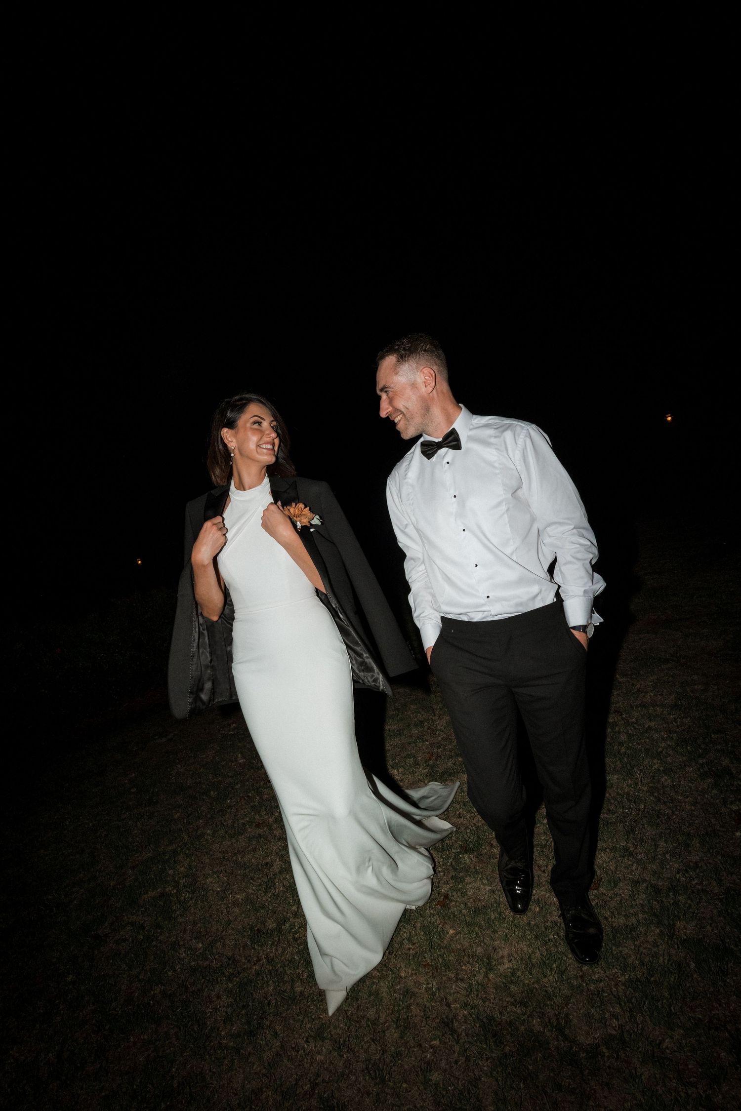 A nighttime wedding portrait of a couple walking and laughing together.