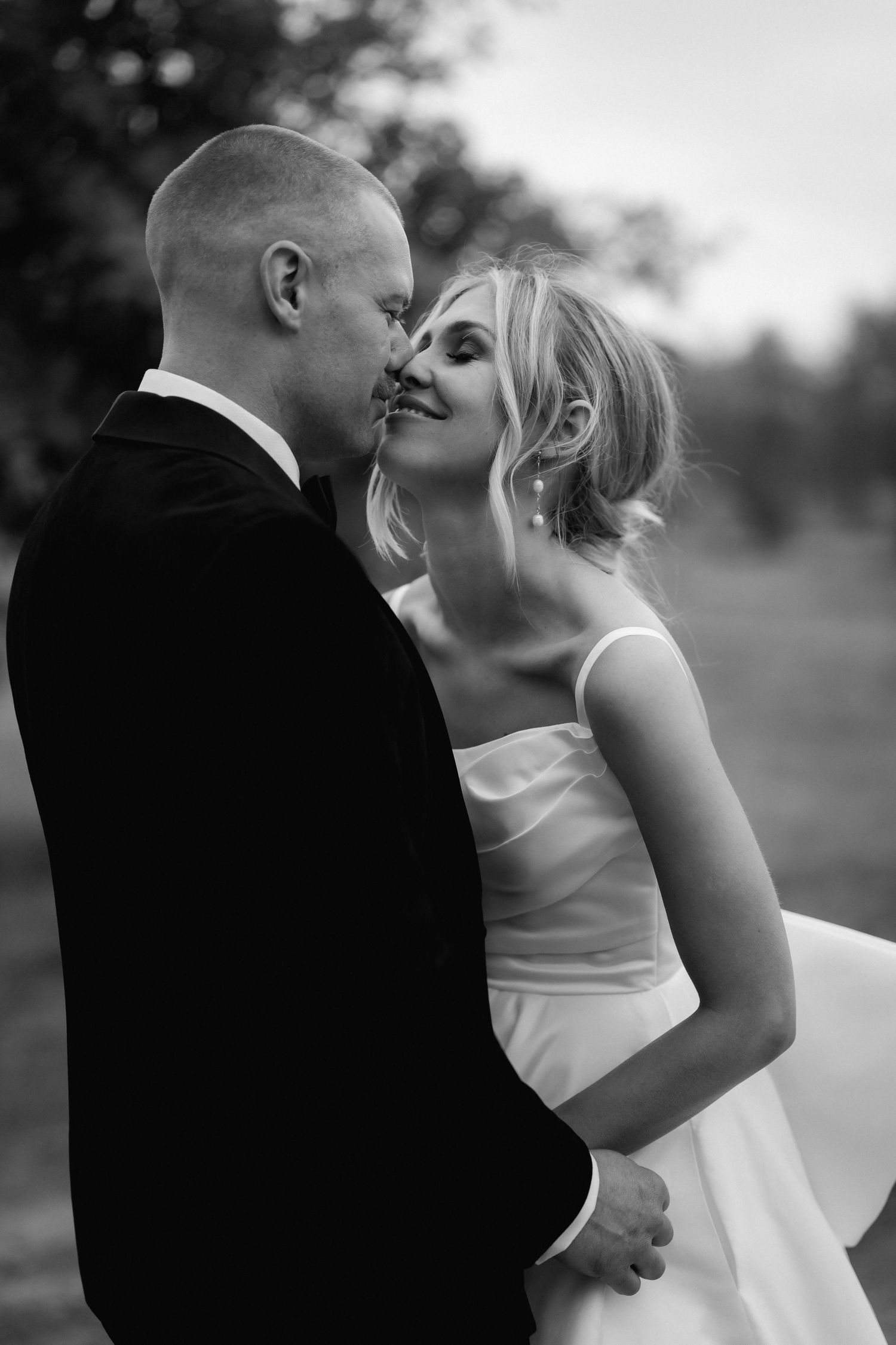 Black and white romantic portrait of newlyweds embracing outdoors at golden hour.