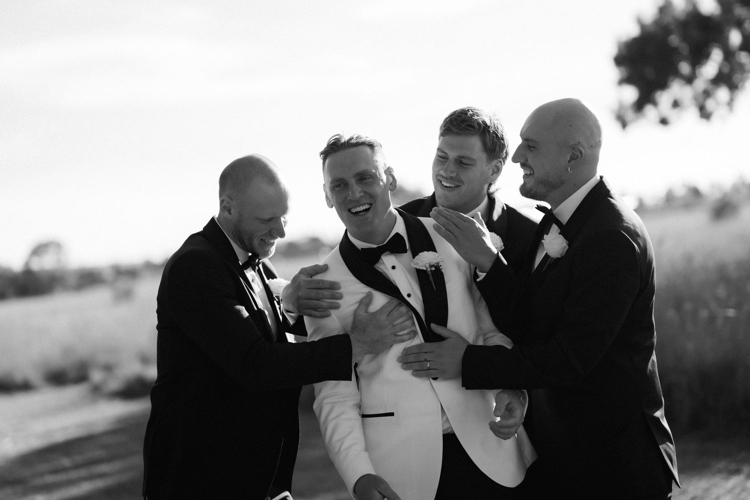 A black and white wedding photo collage showing emotional moments between the couple and their wedding party.