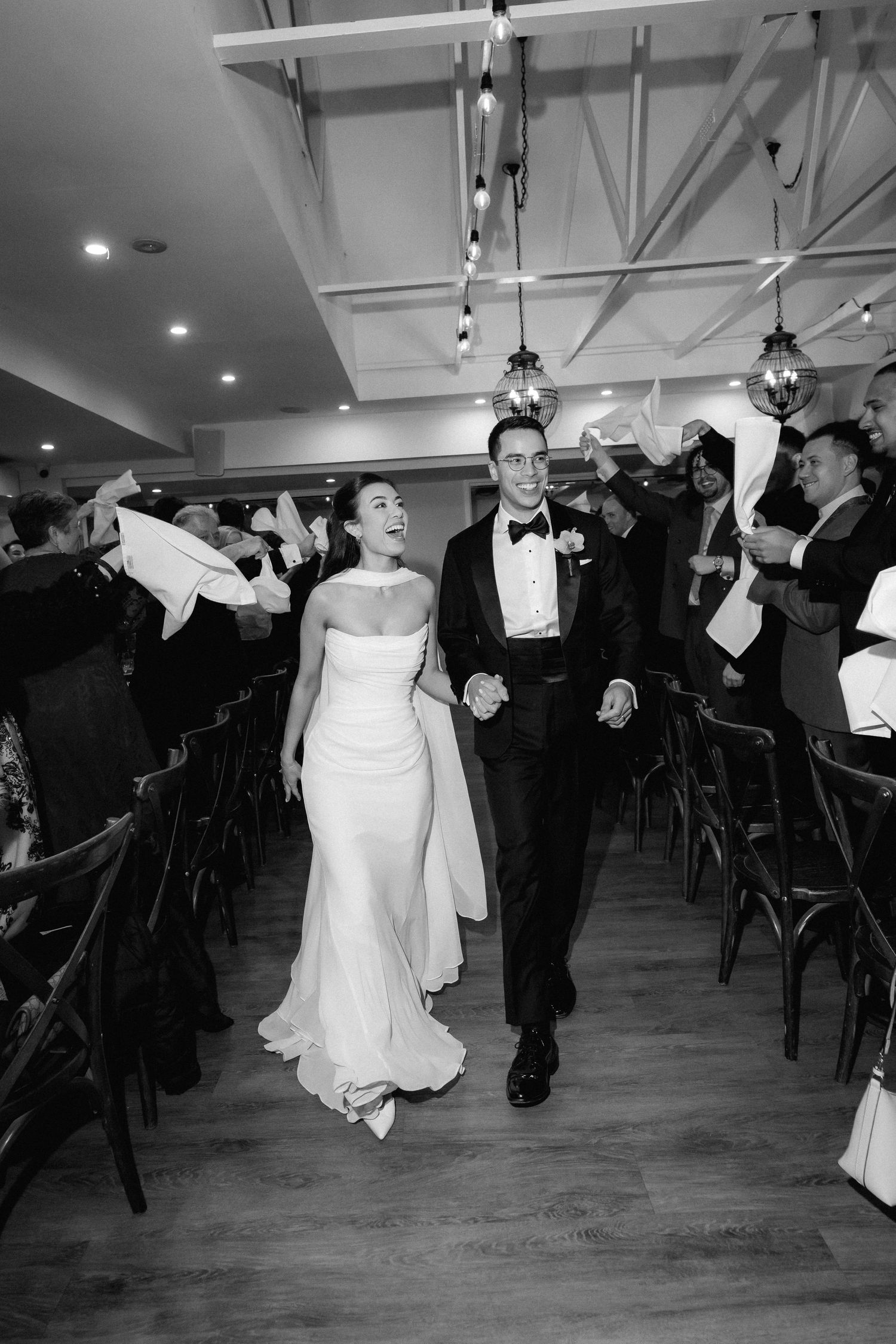 Black and white photo of bride and groom making grand entrance at wedding reception.