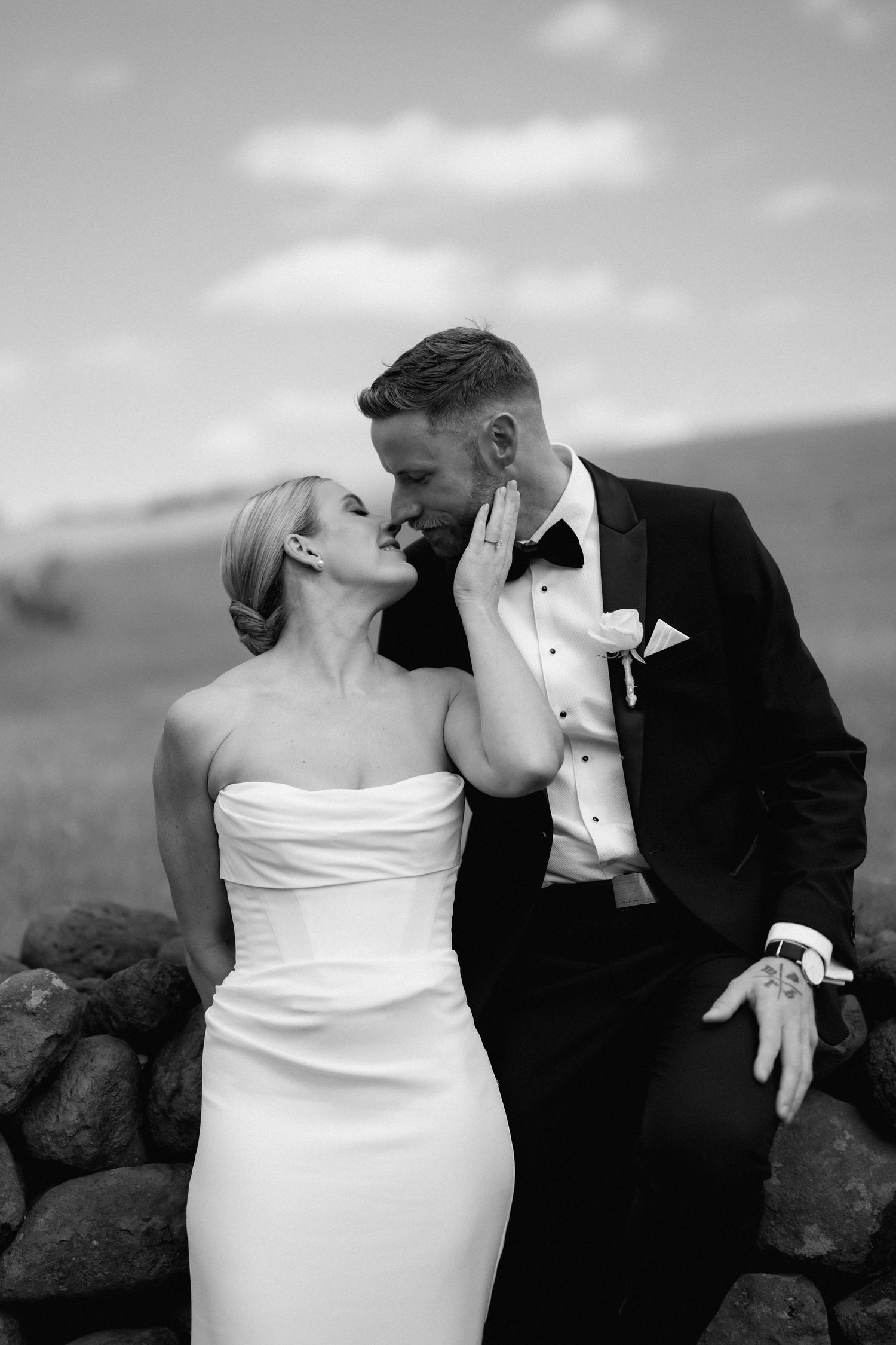 Black and white romantic wedding photos show intimate kisses between newlyweds against a scenic backdrop.