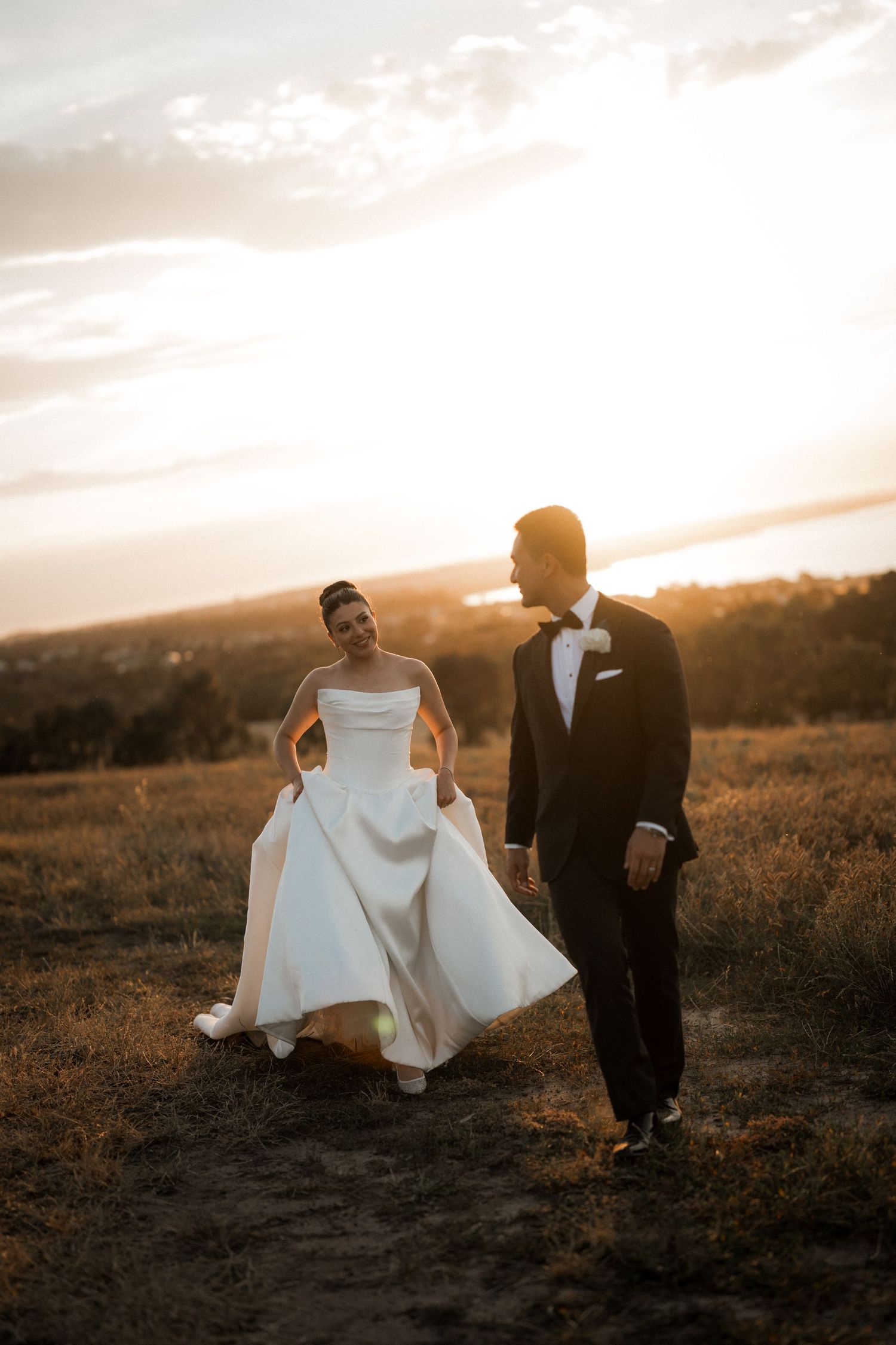 Romantic sunset wedding portraits on a hilltop with dramatic lighting.
