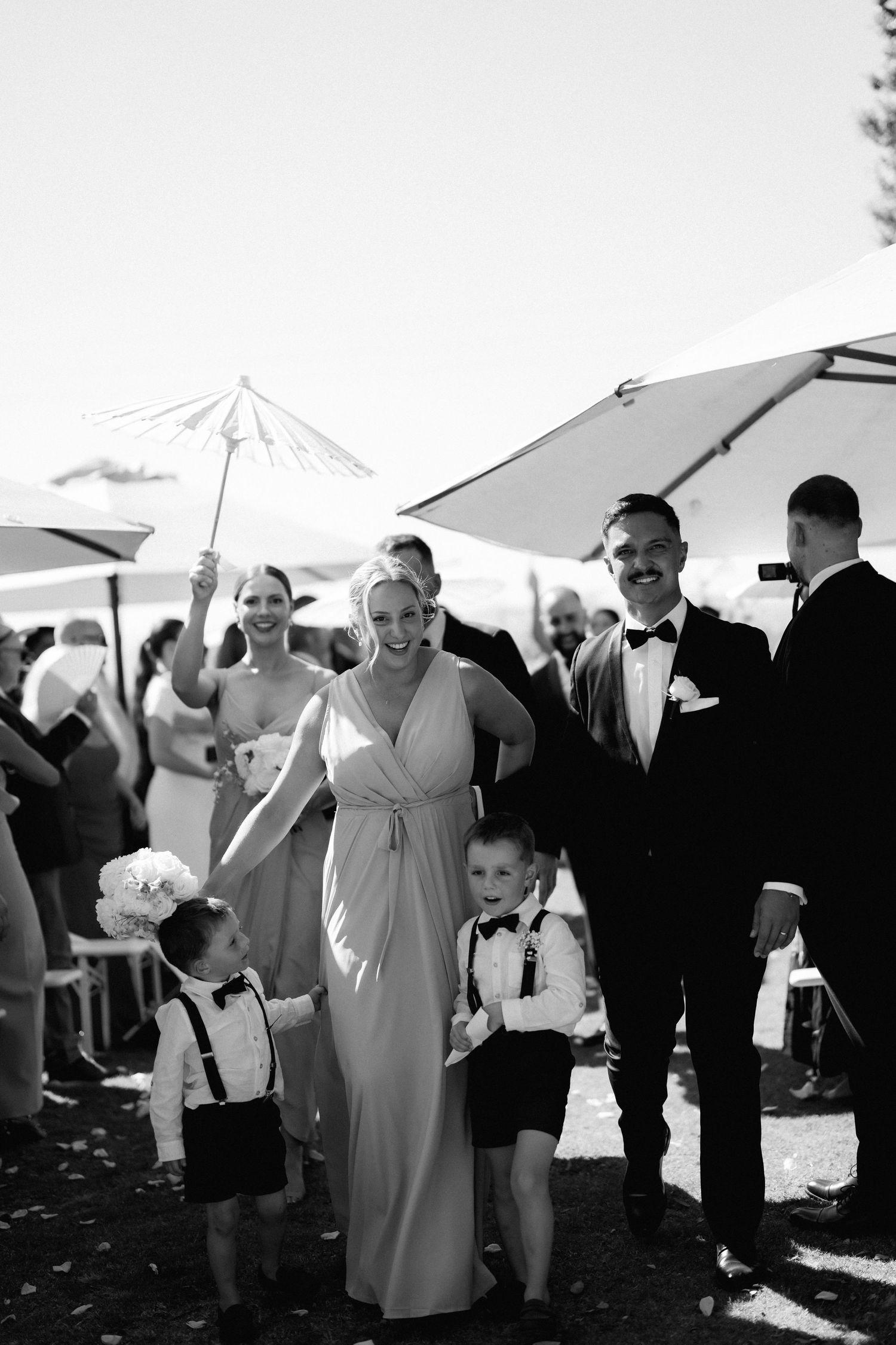 Wedding guests gather under white tents during an outdoor celebration.