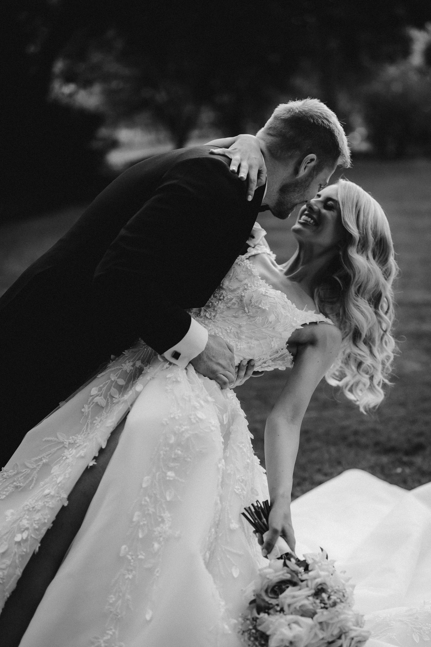 Dramatic black and white wedding portrait showing a romantic dip with flowing dress.