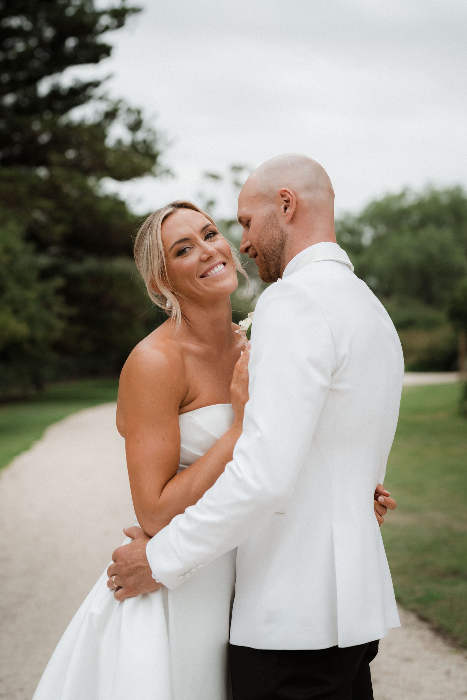 Romantic moment between couple in wedding attire on garden path.
