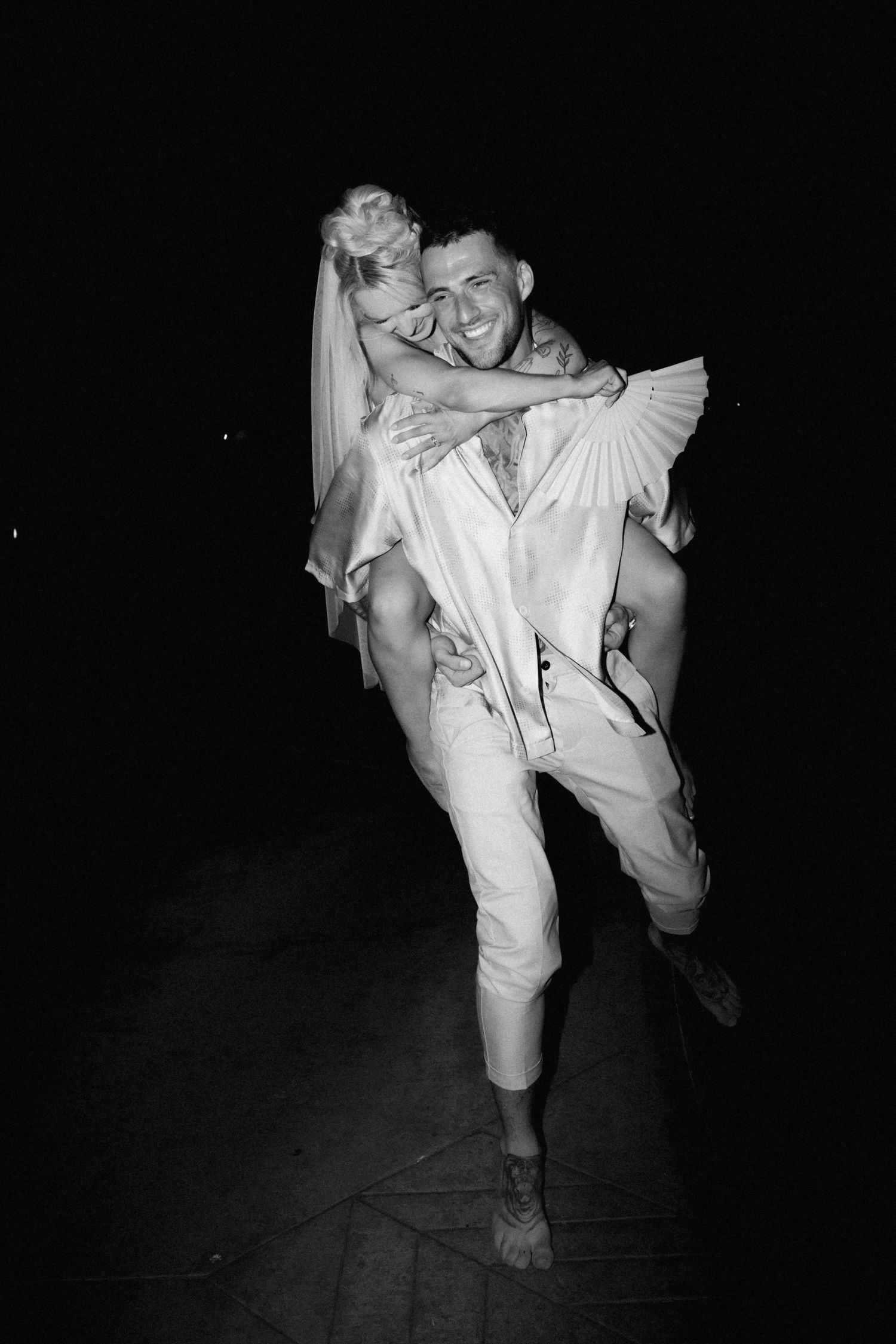 A black and white photo captures a joyful moment during a wedding reception celebration.