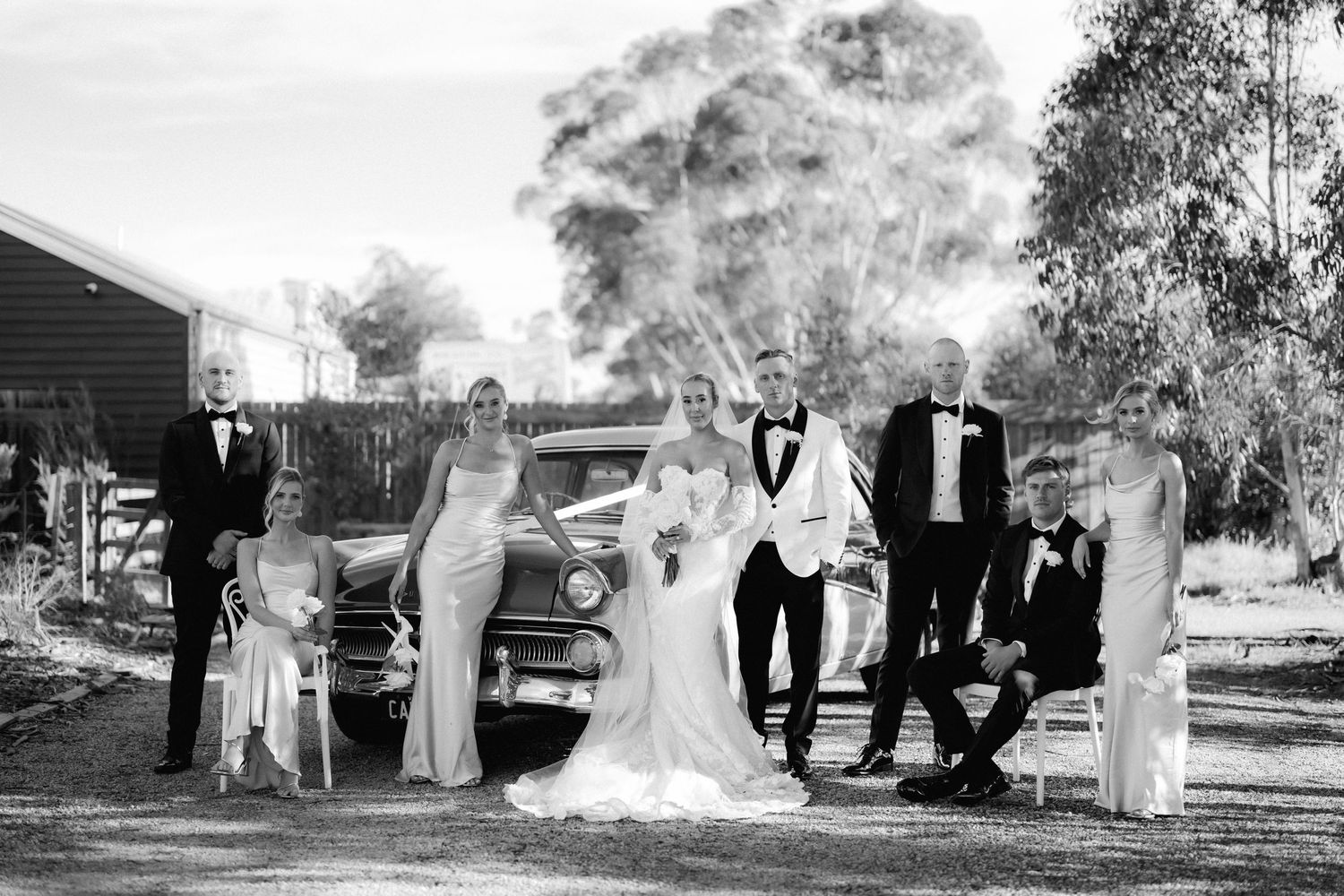 A black and white wedding photo sequence showing a bridal party walking and posing outdoors in formal attire.