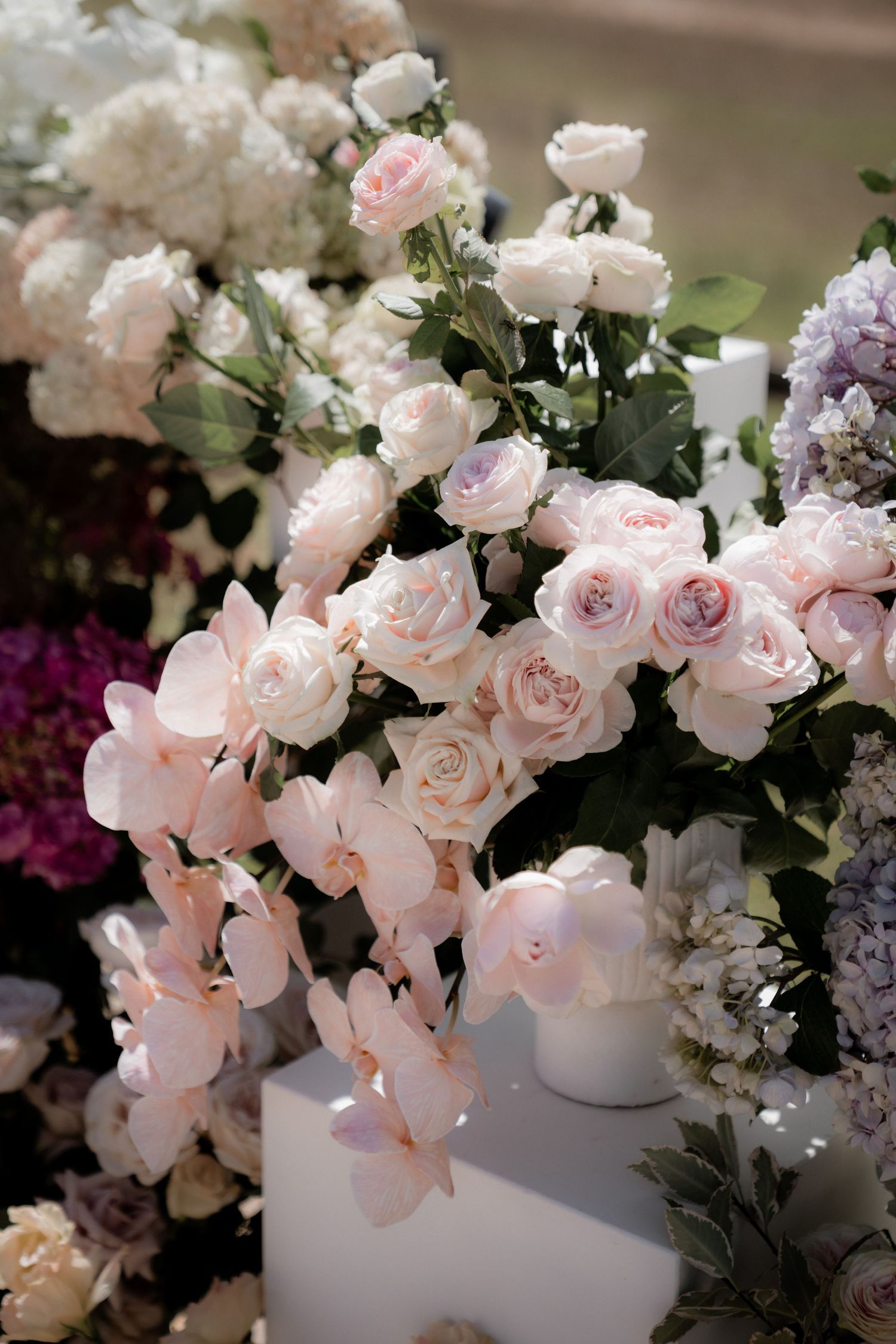 Delicate pink roses and floral arrangements adorn a white table setting.