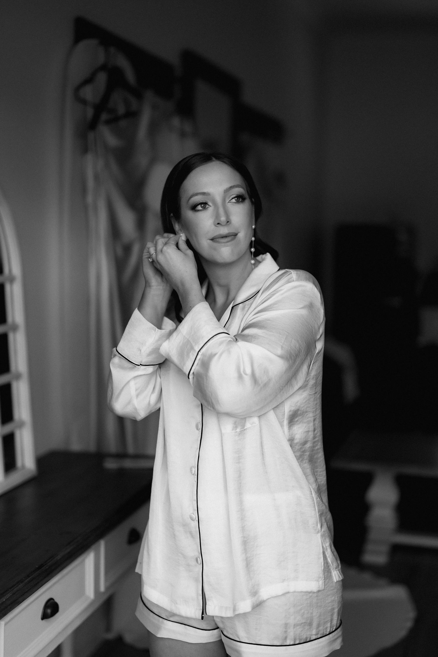 Elegant black and white portrait of a woman in a white button-down shirt posing against a dark background.