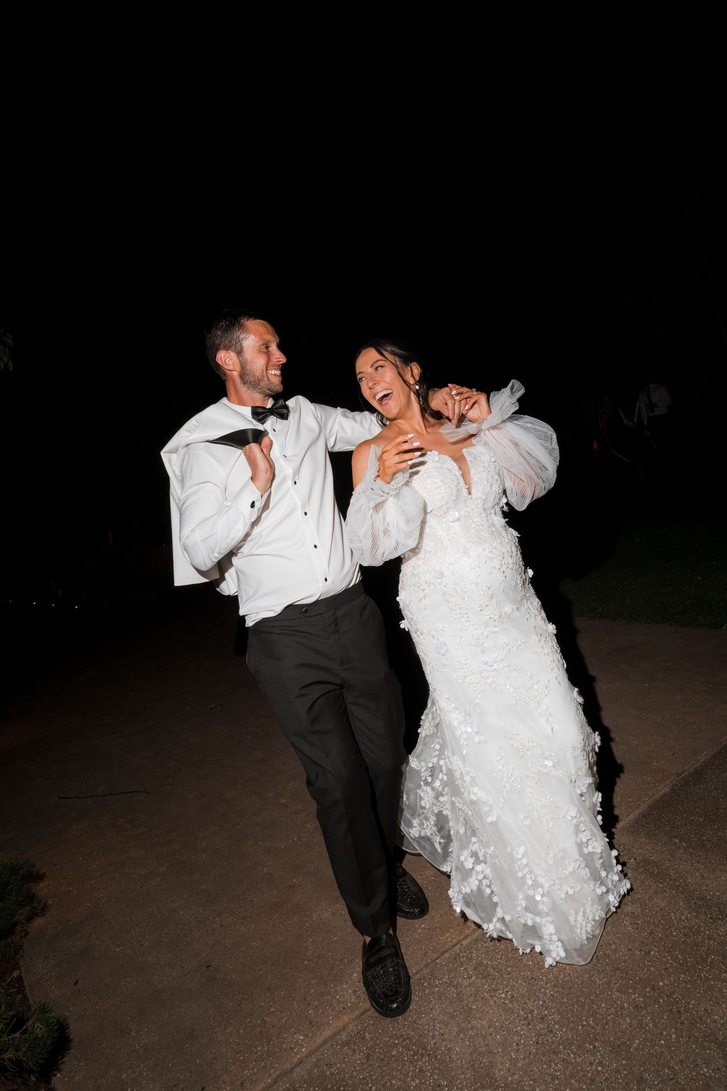 A joyful couple running together at night after their wedding celebration.